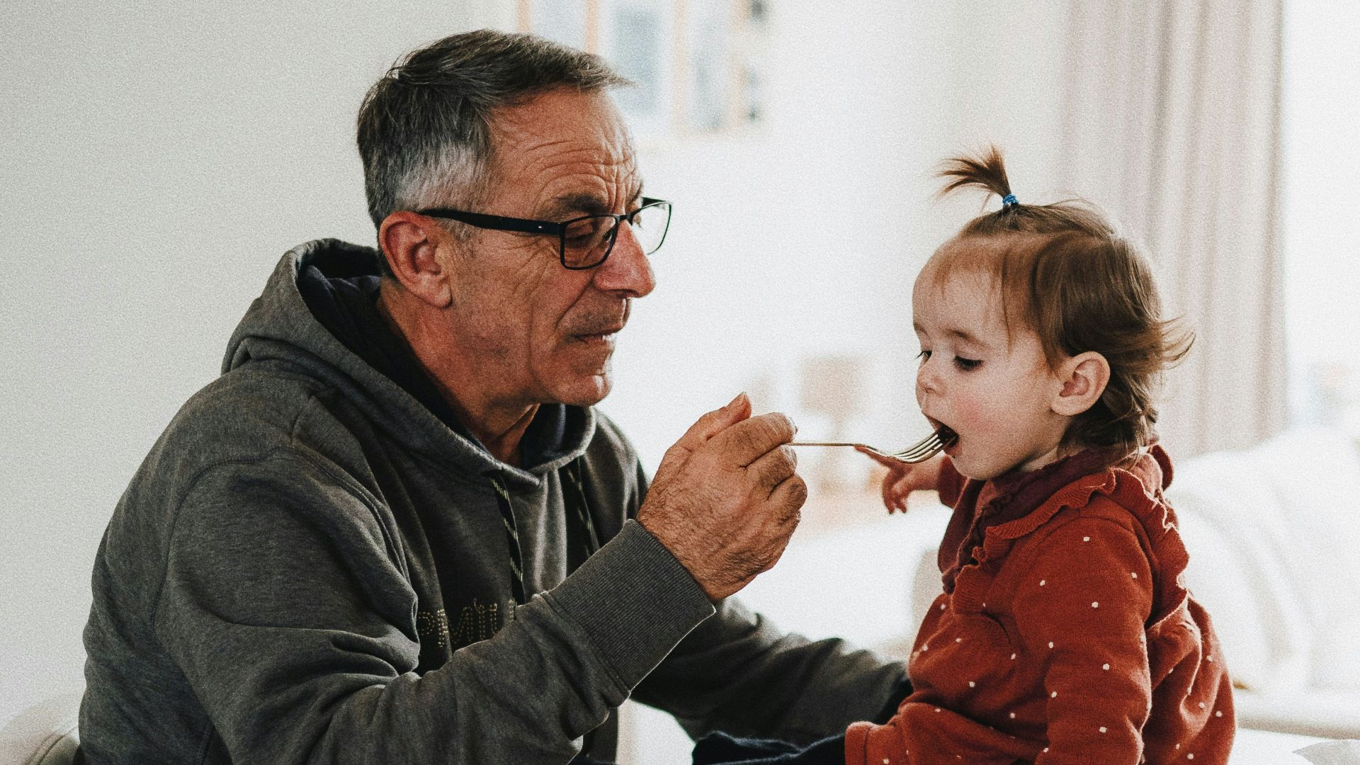 a man feeding a little girl with a spoon