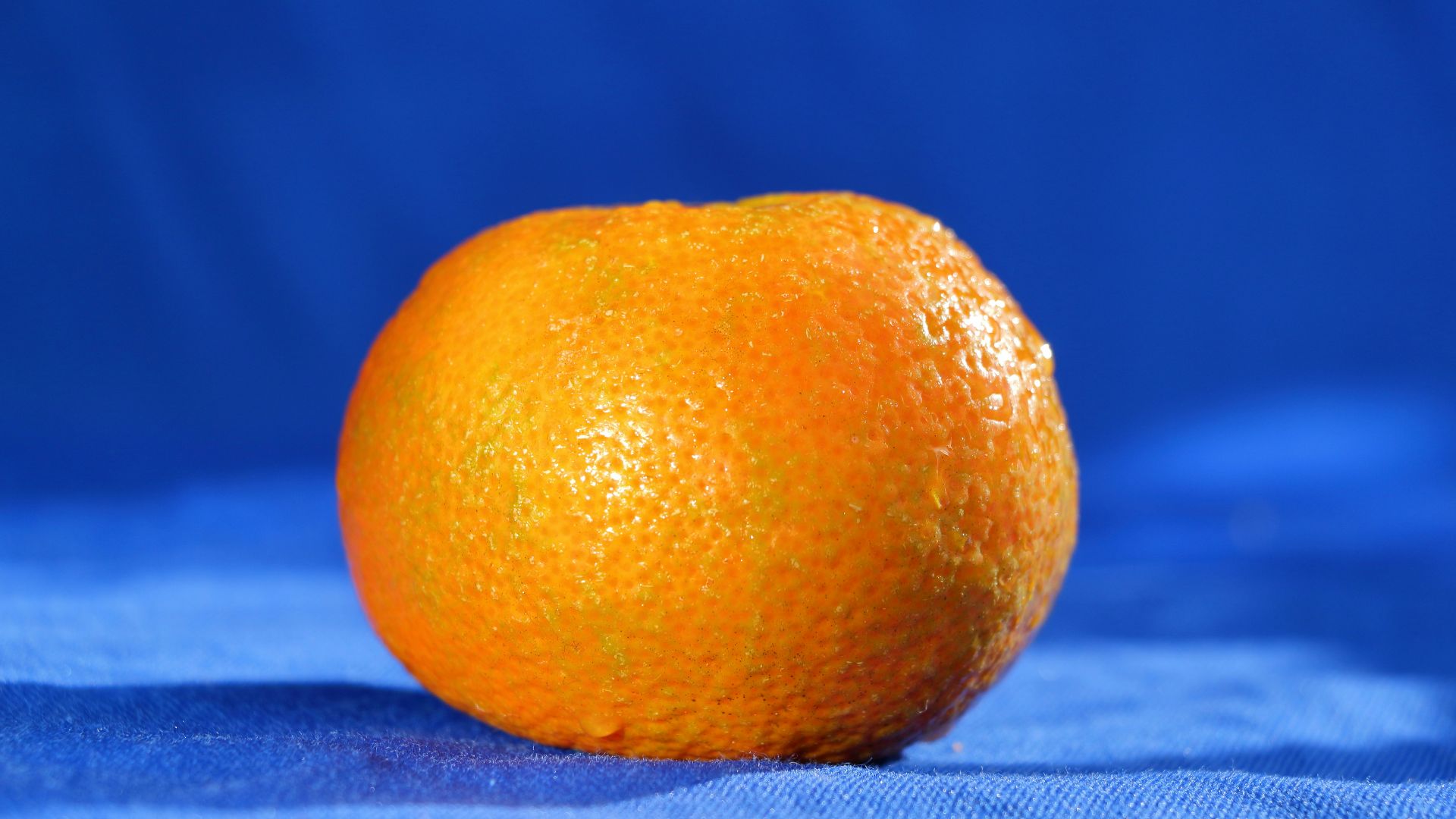 an orange sitting on top of a blue cloth