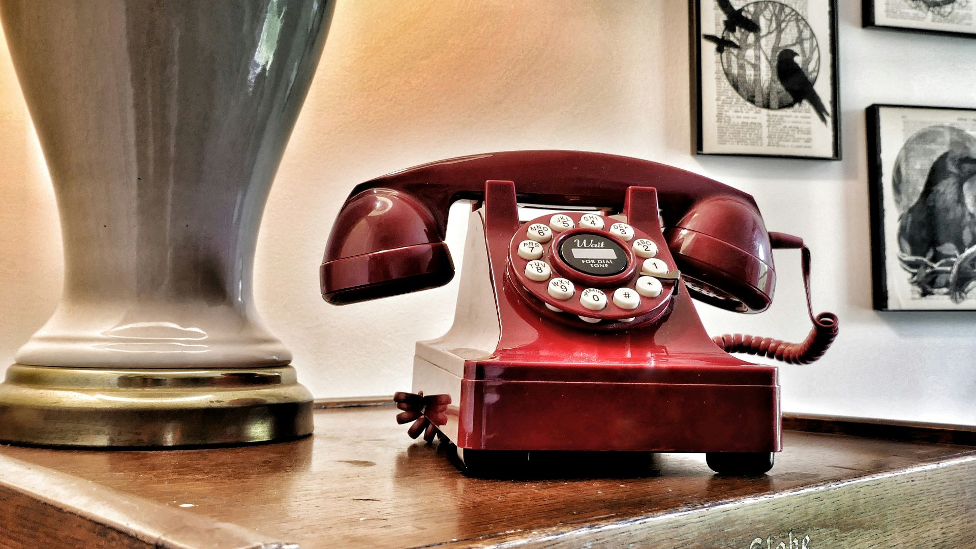 Vintage red rotary phone on wooden surface