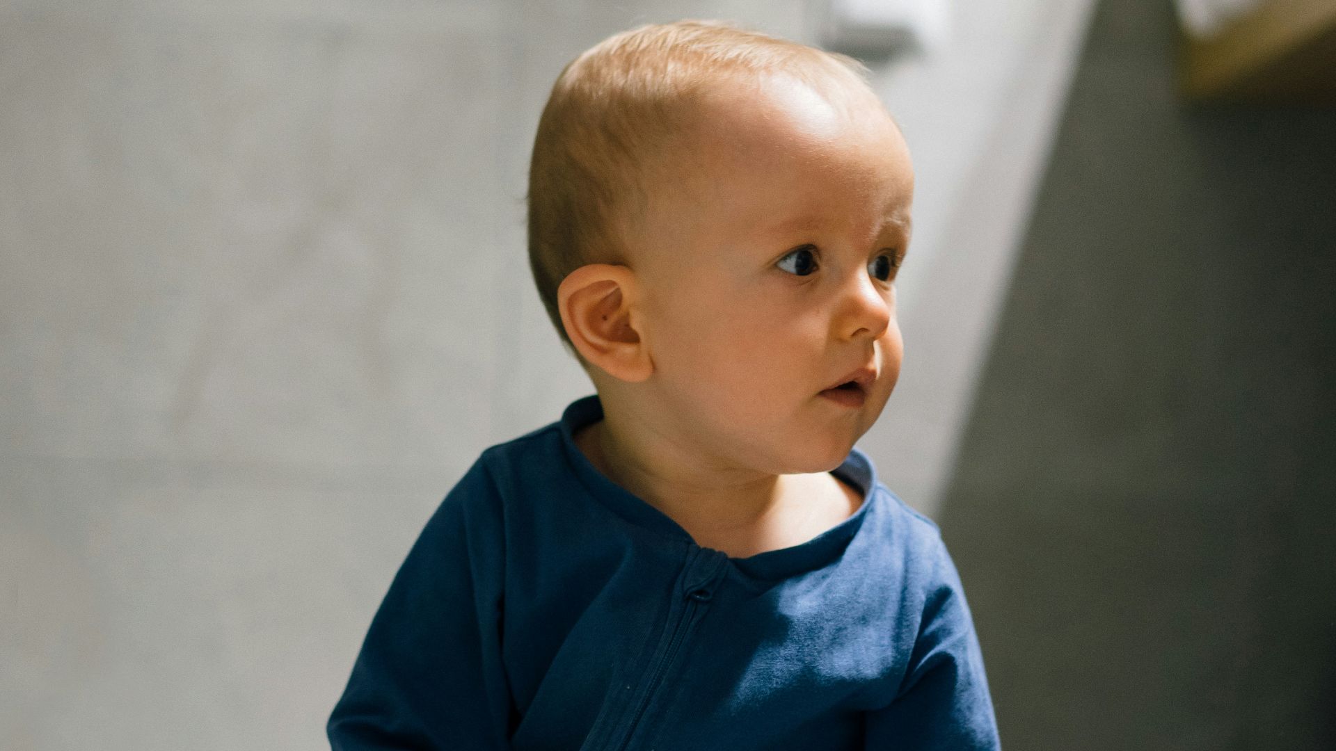 baby in blue long sleeve shirt and blue denim jeans sitting on floor