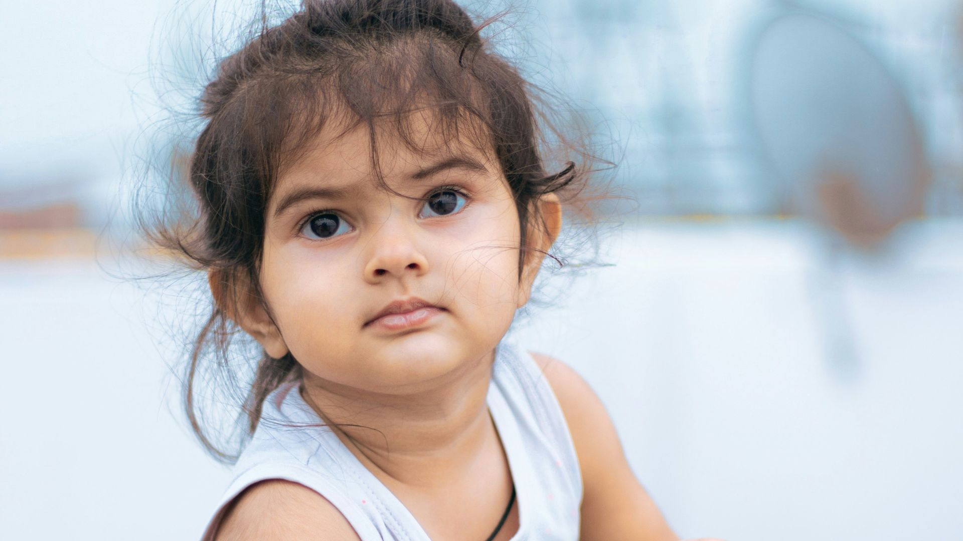 girl in white tank top sitting on brown wooden chair