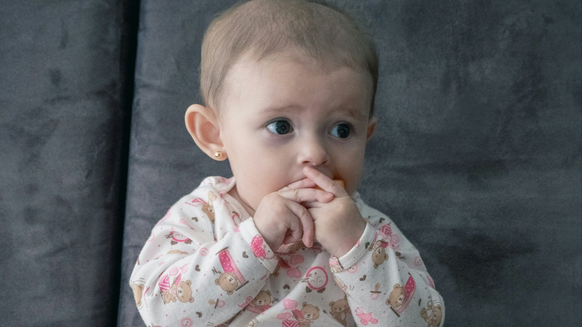 baby in white and pink onesie sitting on green and white ceramic plate