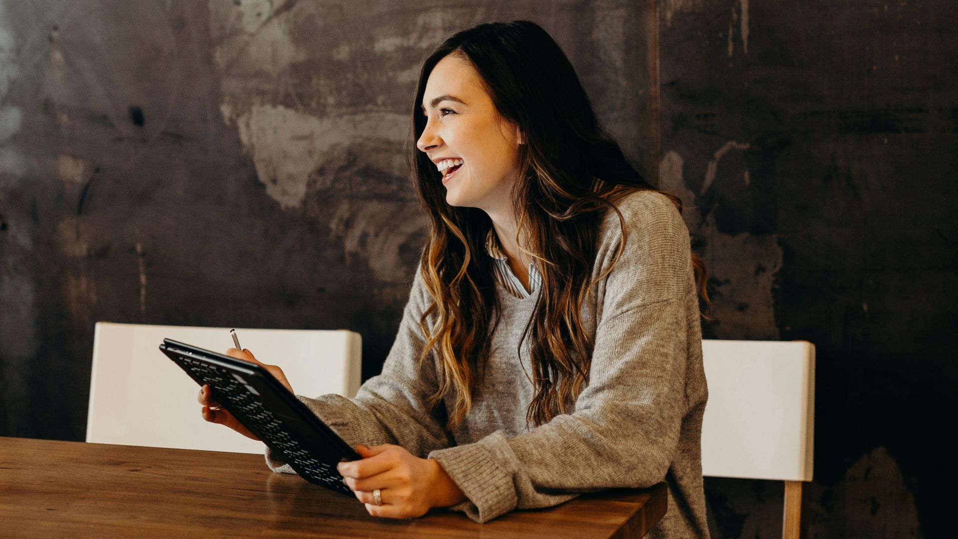 woman sitting around table holding tablet