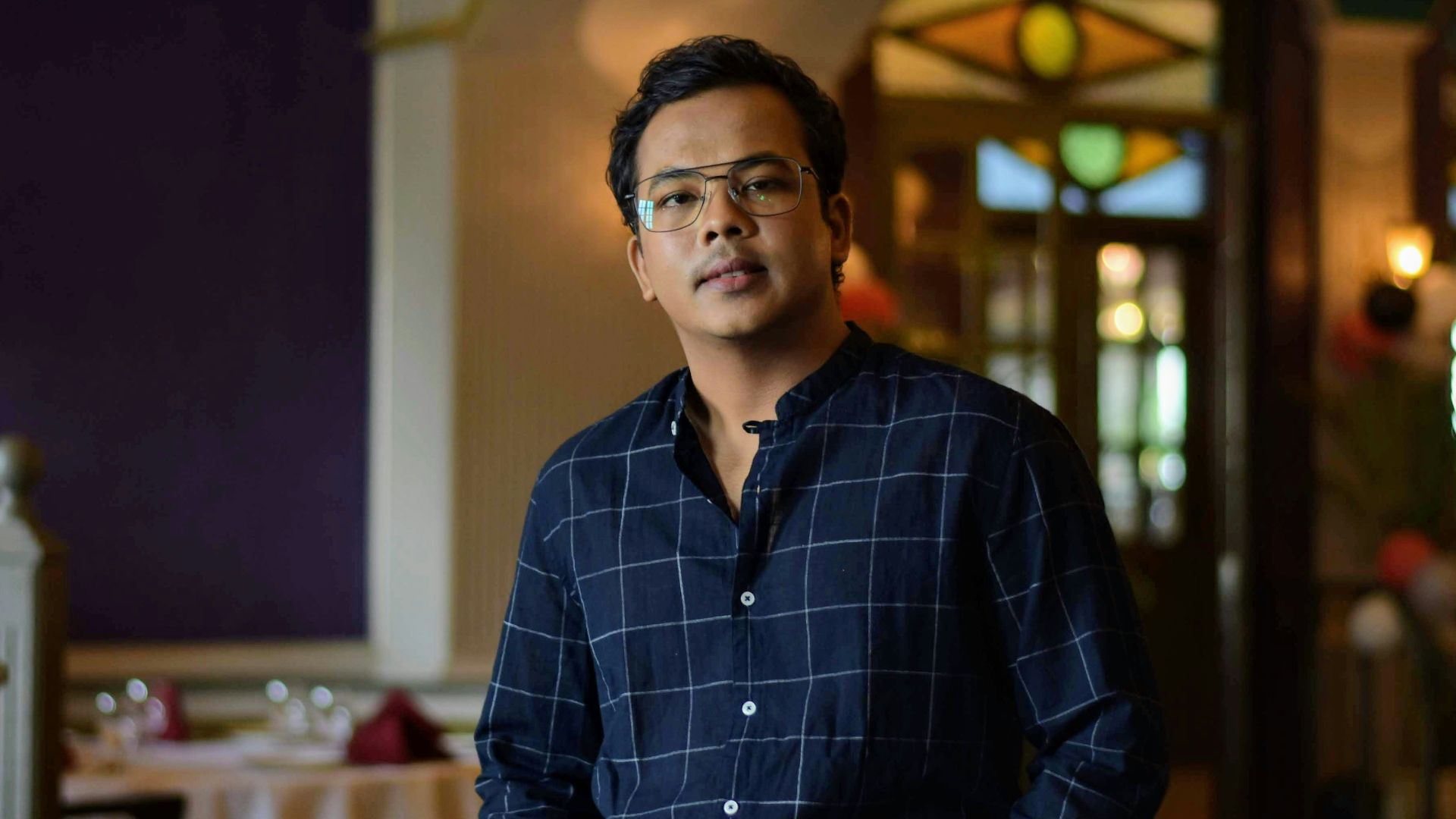 man in blue and white plaid dress shirt sitting on chair