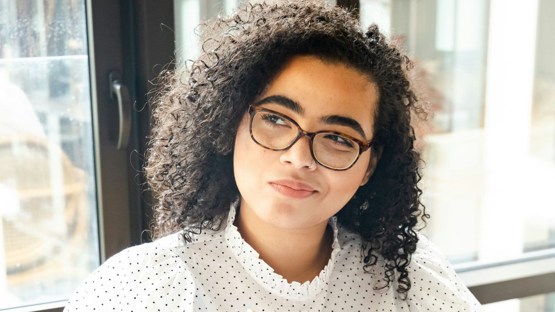woman in white and black polka dot shirt holding blue and white book
