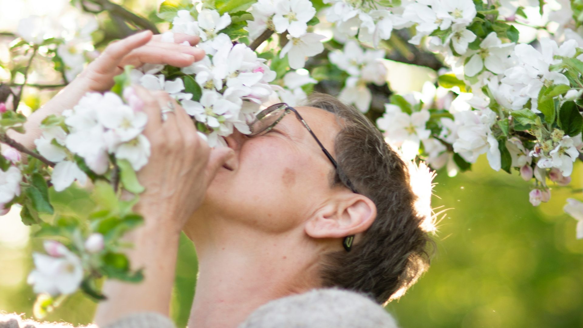 a man is smelling a tree with white flowers