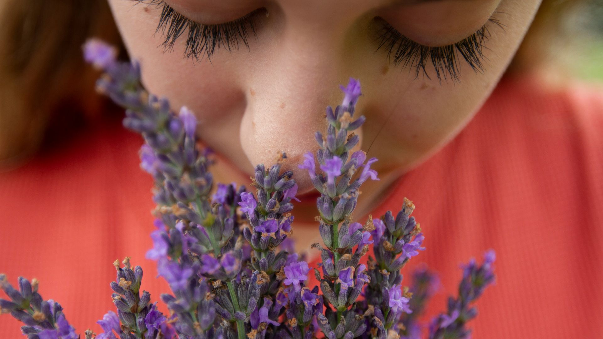 woman in orange shirt with purple flowers on her head