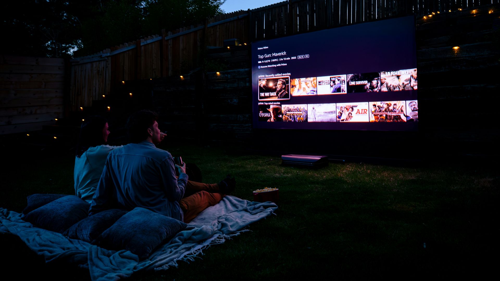 Two people sitting on a blanket watching a movie
