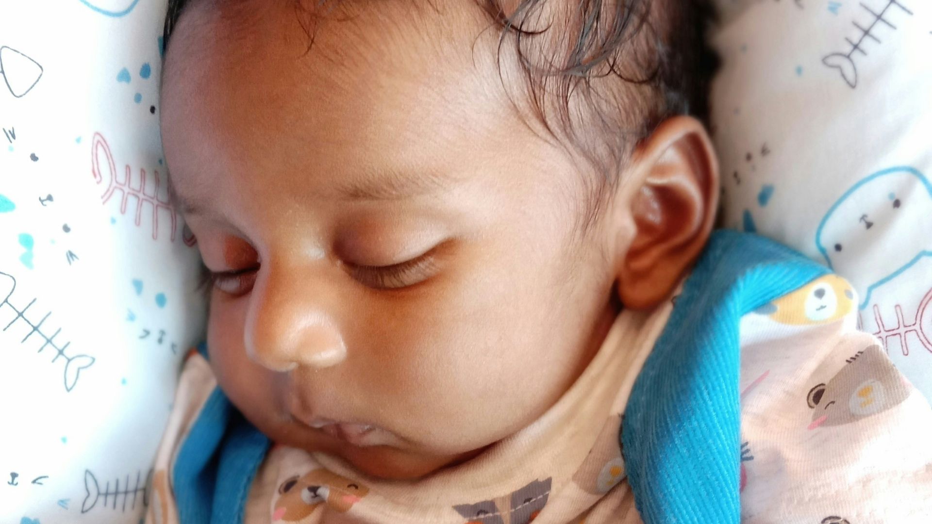 baby in blue and white stripe shirt lying on white textile