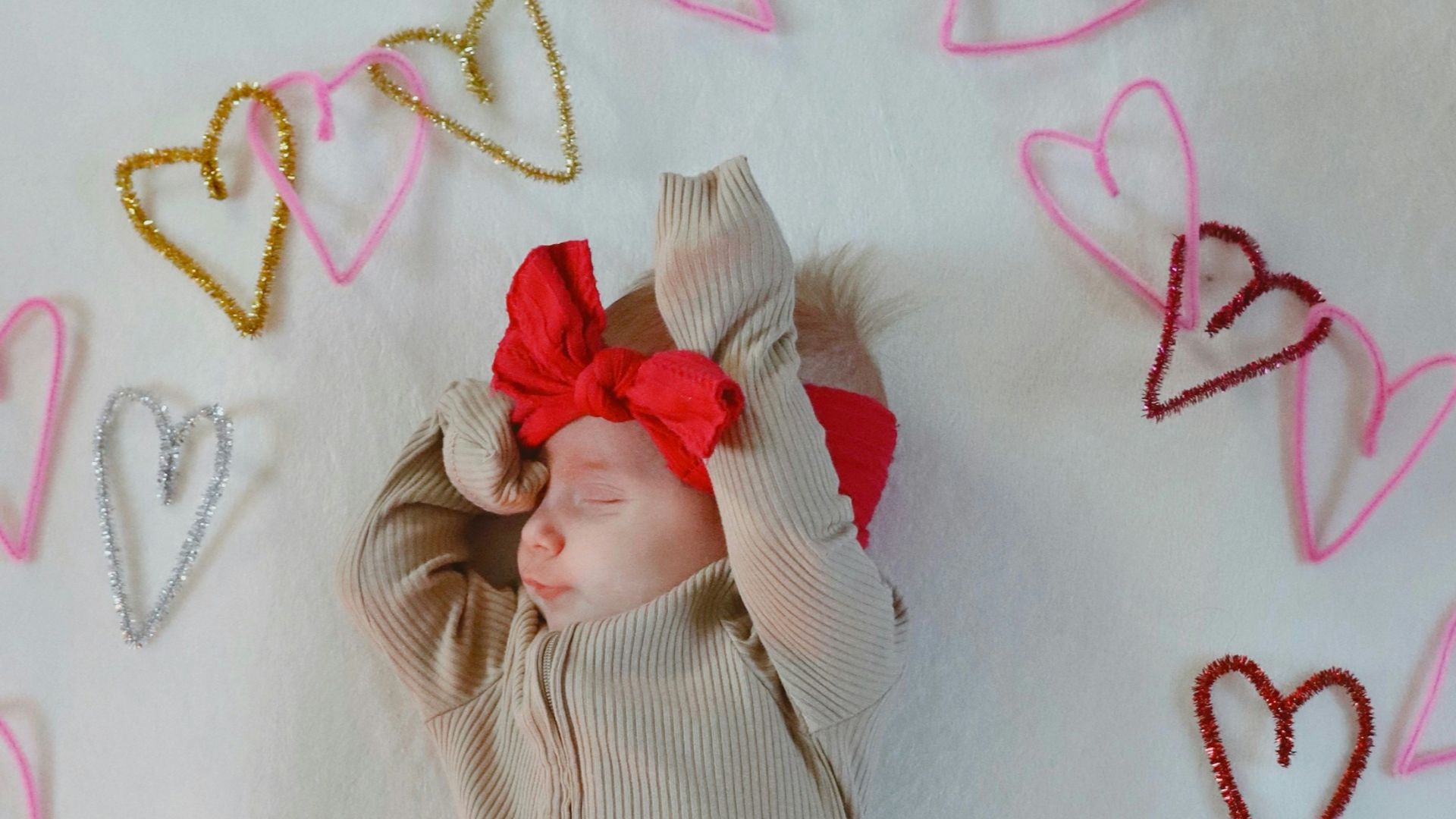 A baby is laying on a blanket with hearts around it