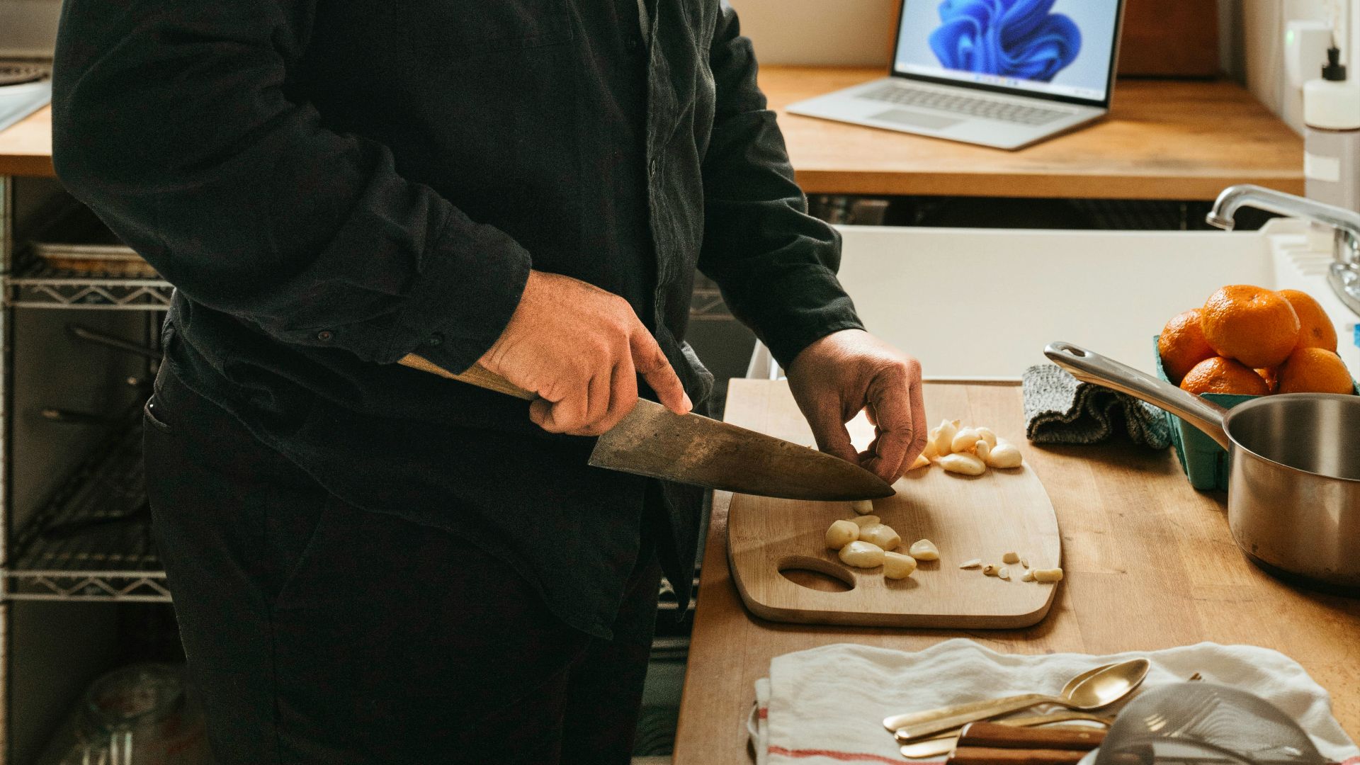 a man cutting food on a cutting board in a kitchen