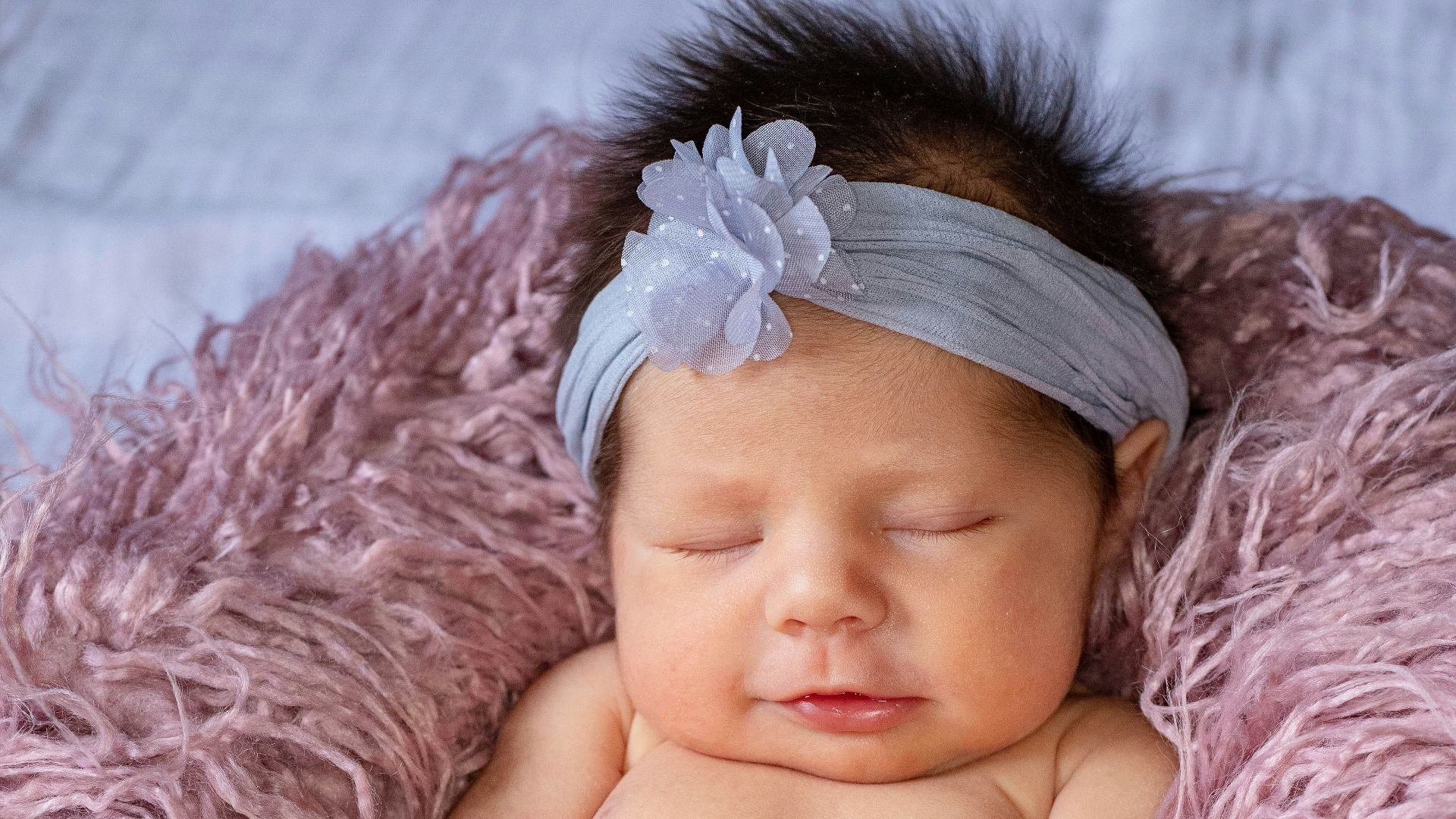 baby lying on pink textile