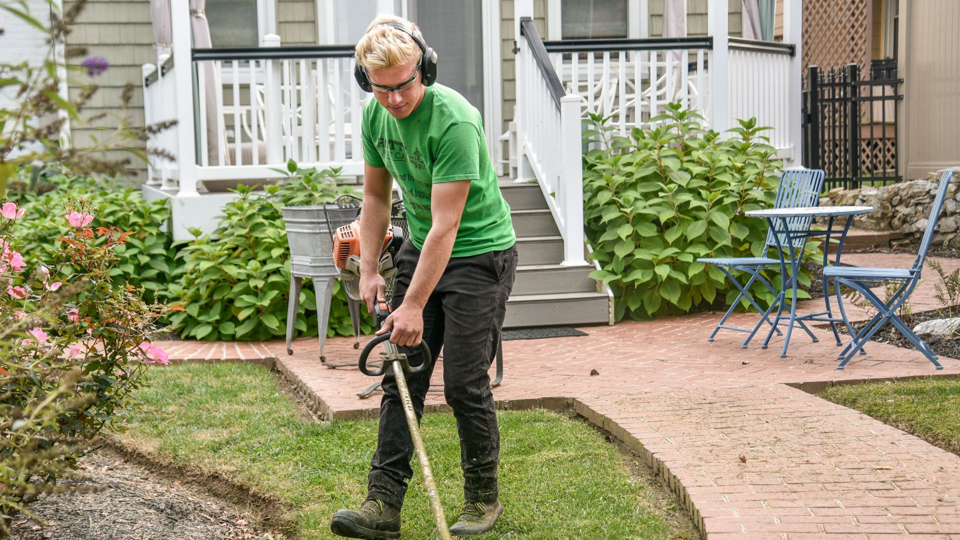 man in green t-shirt and black pants holding black and brown shovel