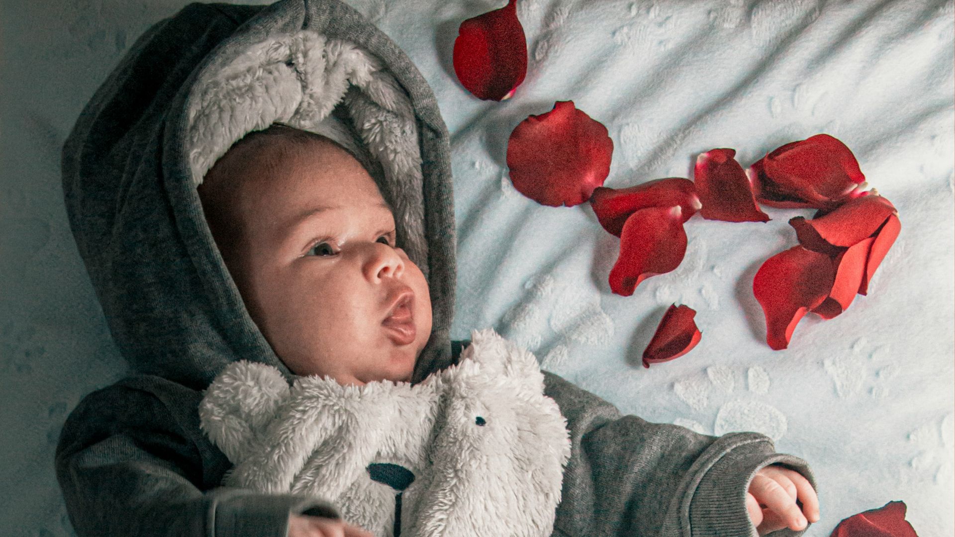 baby in gray and white star print onesie lying on bed