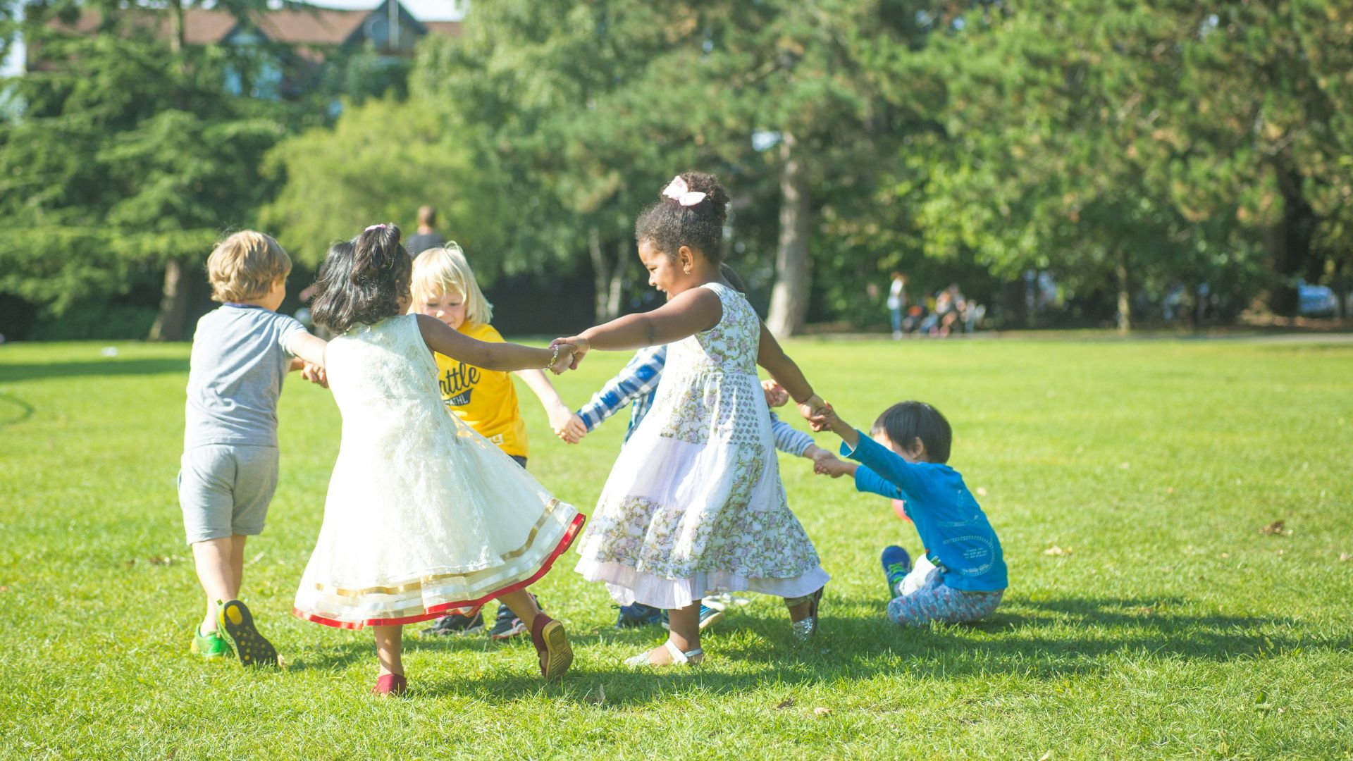 woman in white dress dancing with girl in white dress on green grass field during daytime
