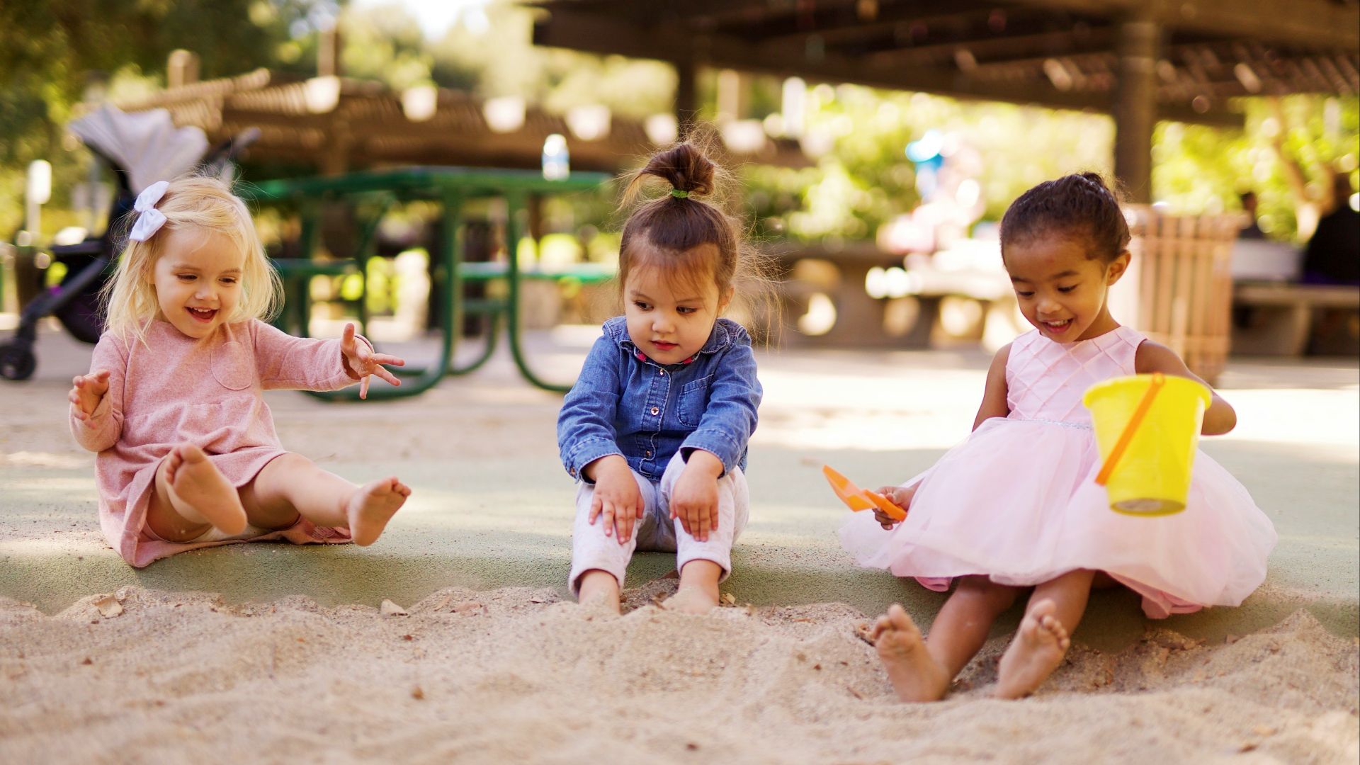 girl in pink dress sitting on brown sand during daytime