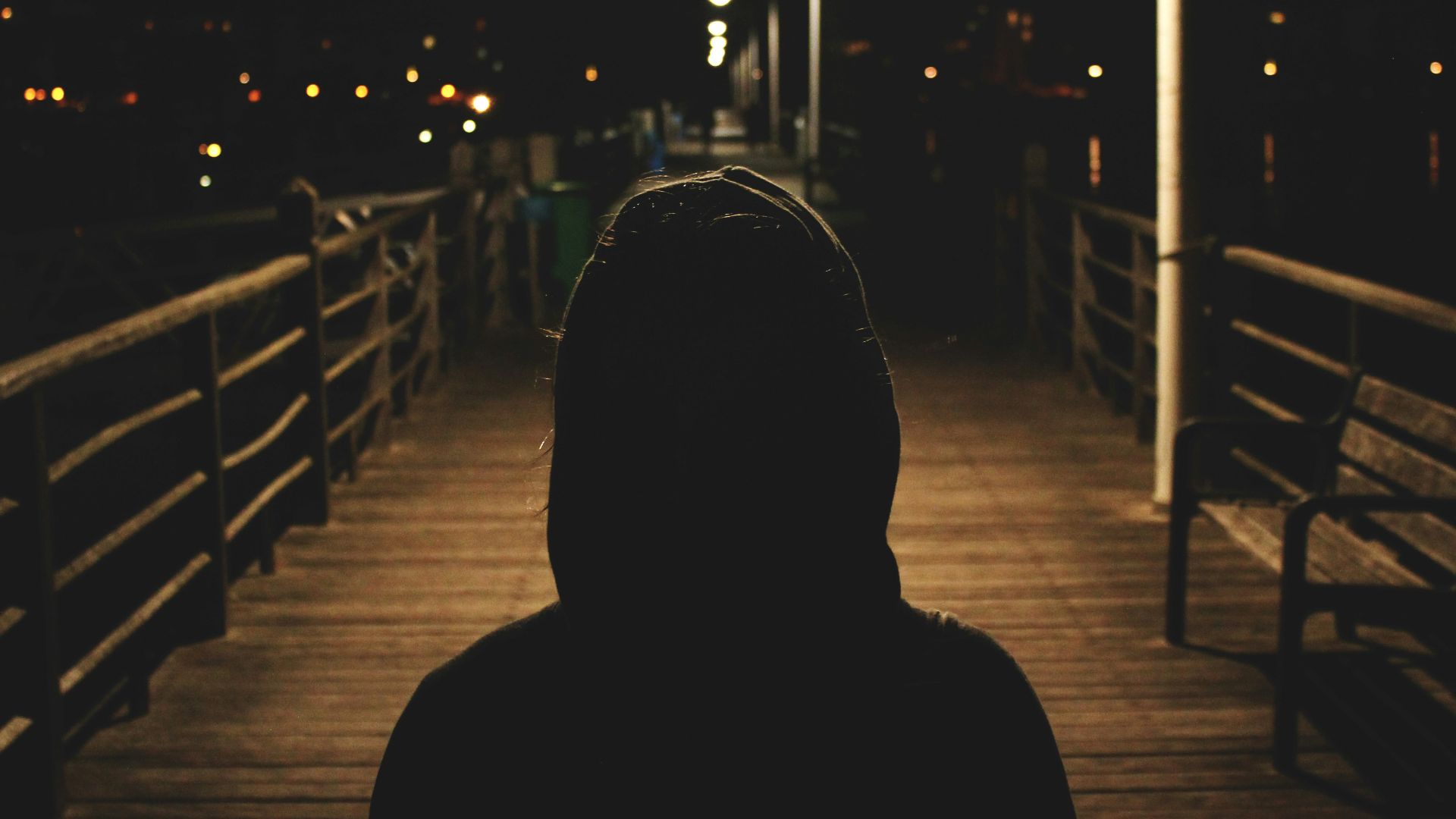 person wearing hooded jacket walking in bridge