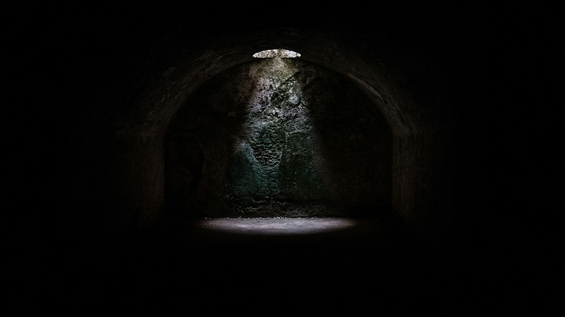 A spotlight coming from a hole in a dark underground cave in Minorca