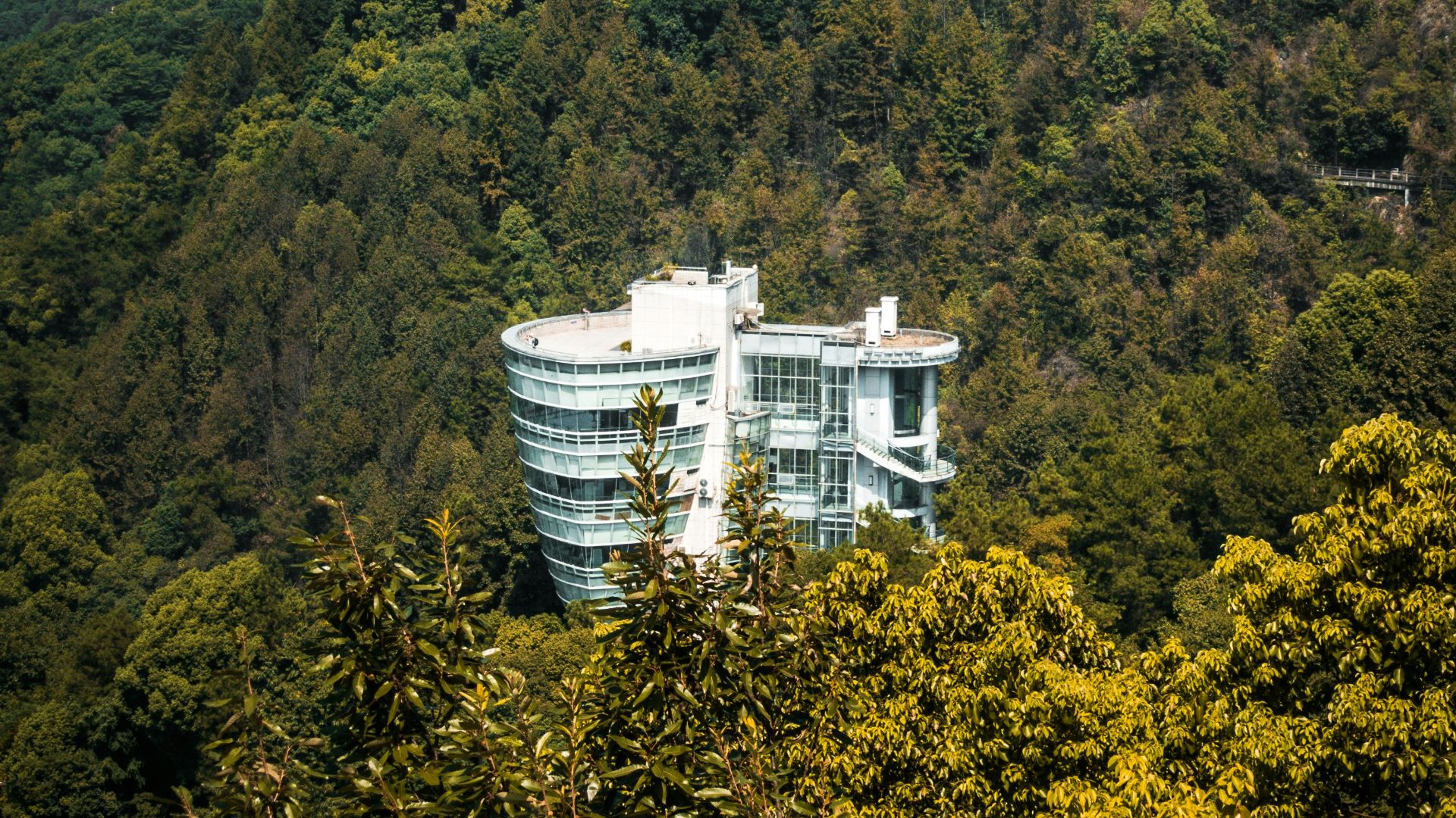 a tall building sitting on top of a lush green hillside