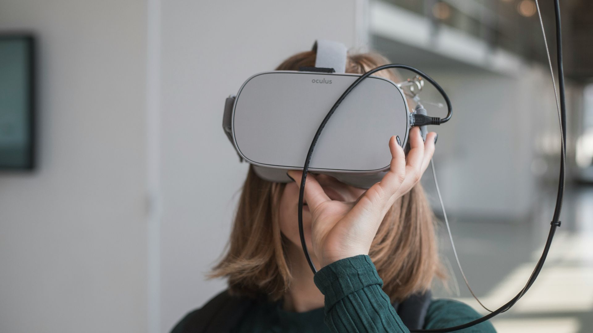 woman in black sweater holding white and black vr goggles