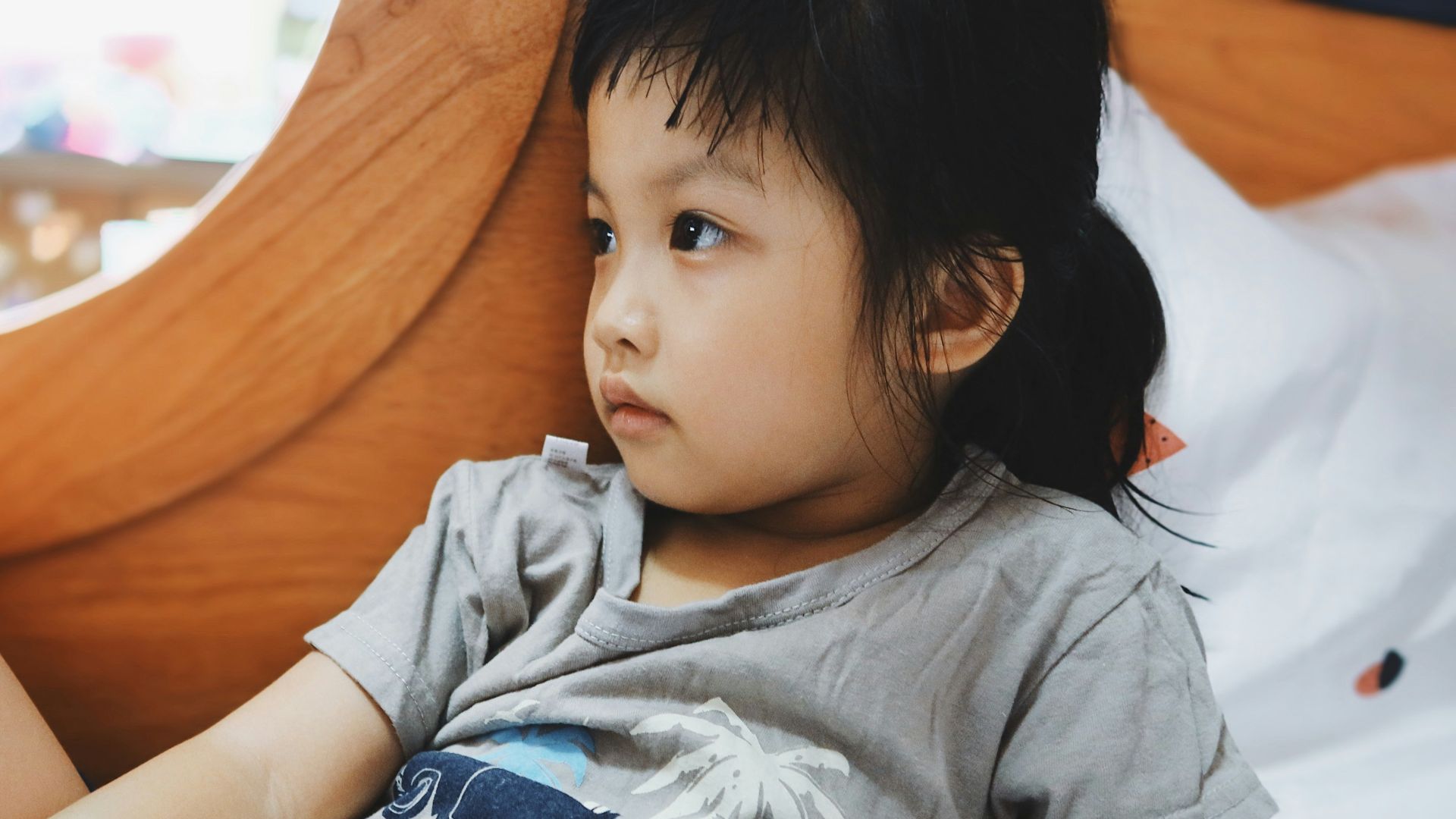 boy in gray crew neck t-shirt lying on bed