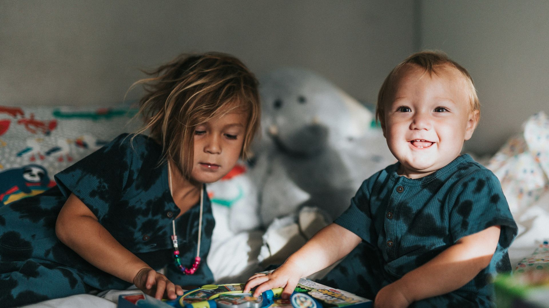 girl in blue and black crew neck t-shirt sitting beside white polar bear plush toy