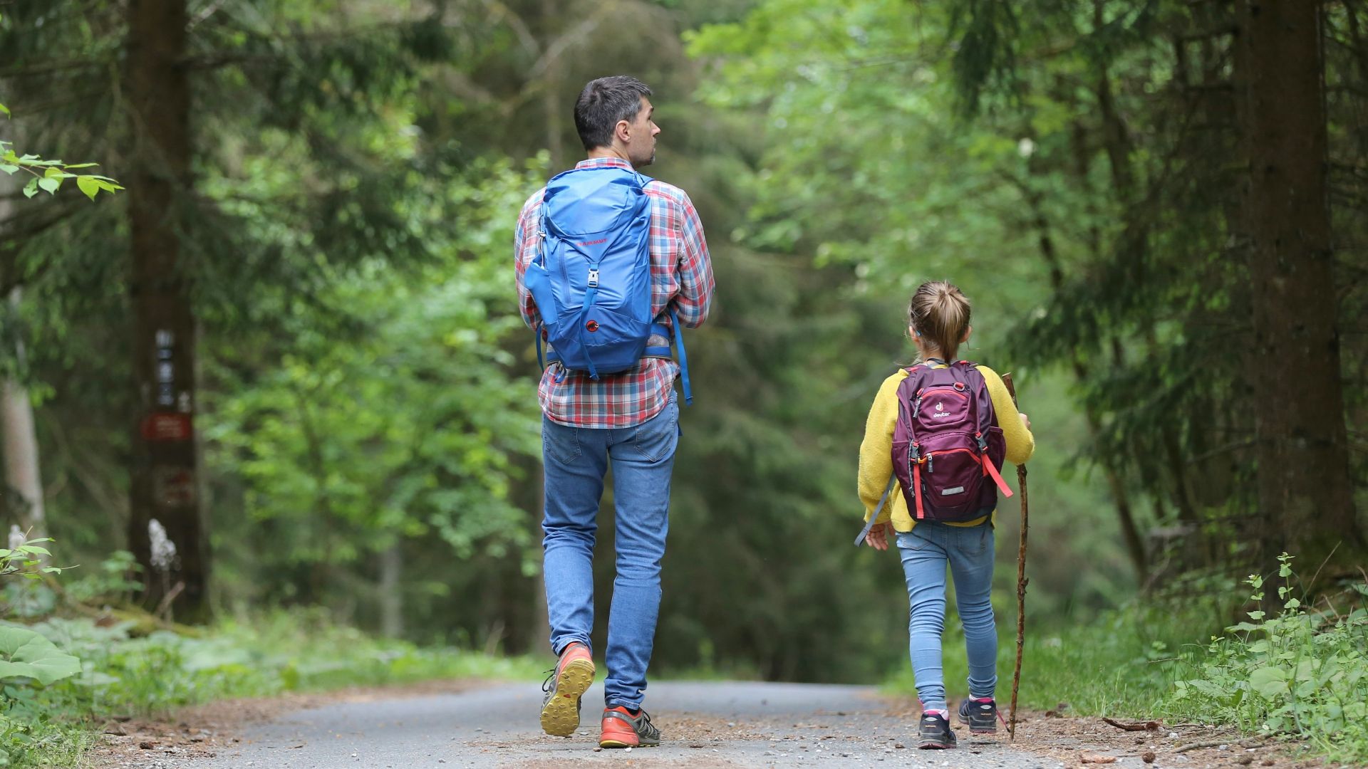 man in blue jacket and blue denim jeans walking on dirt road during daytime