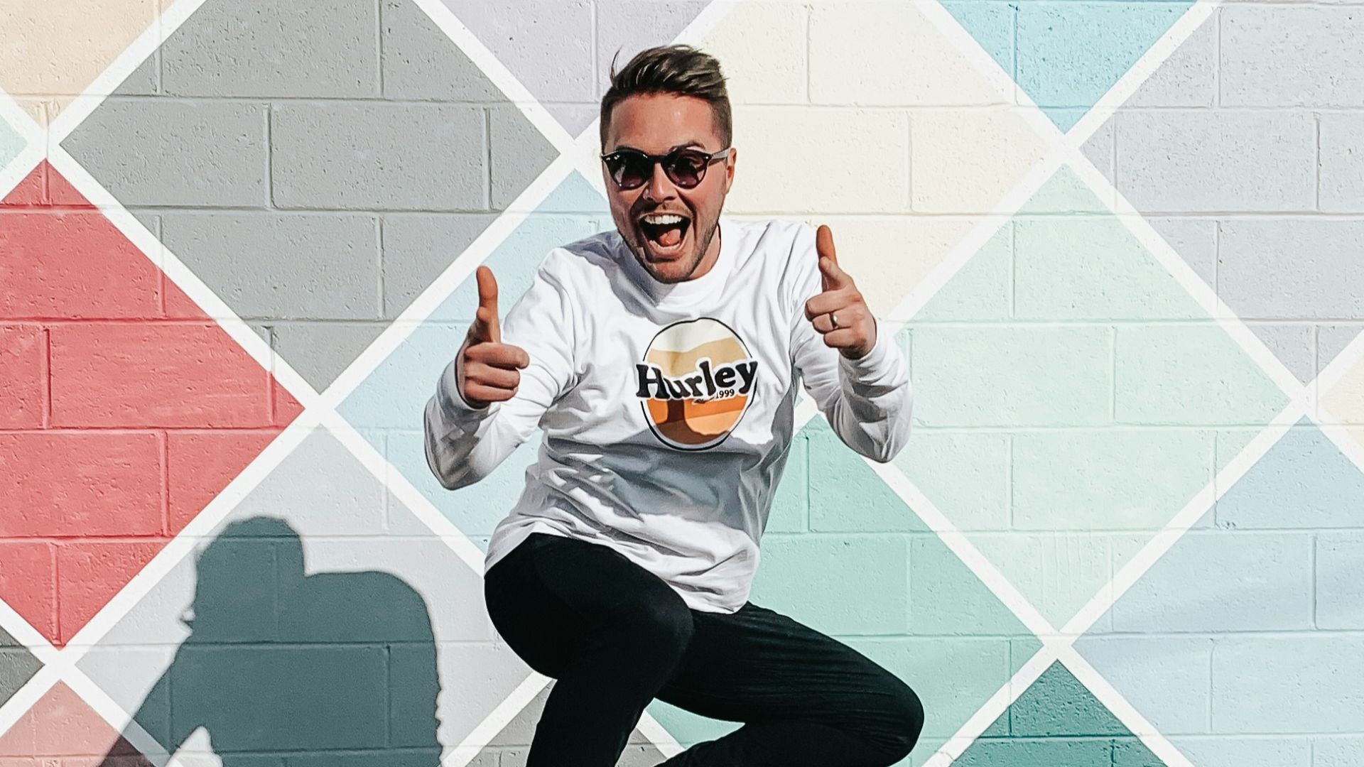 man in white and orange crew neck t-shirt and black pants sitting on blue and