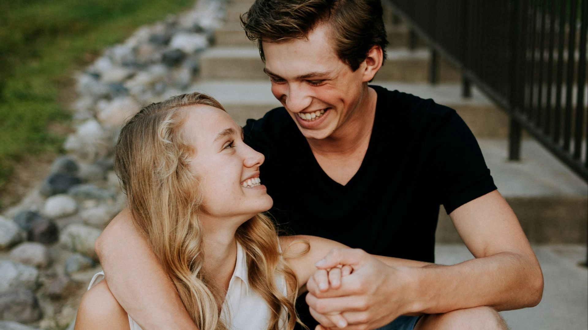 man holding the hand of a woman while siting on concrete staircase