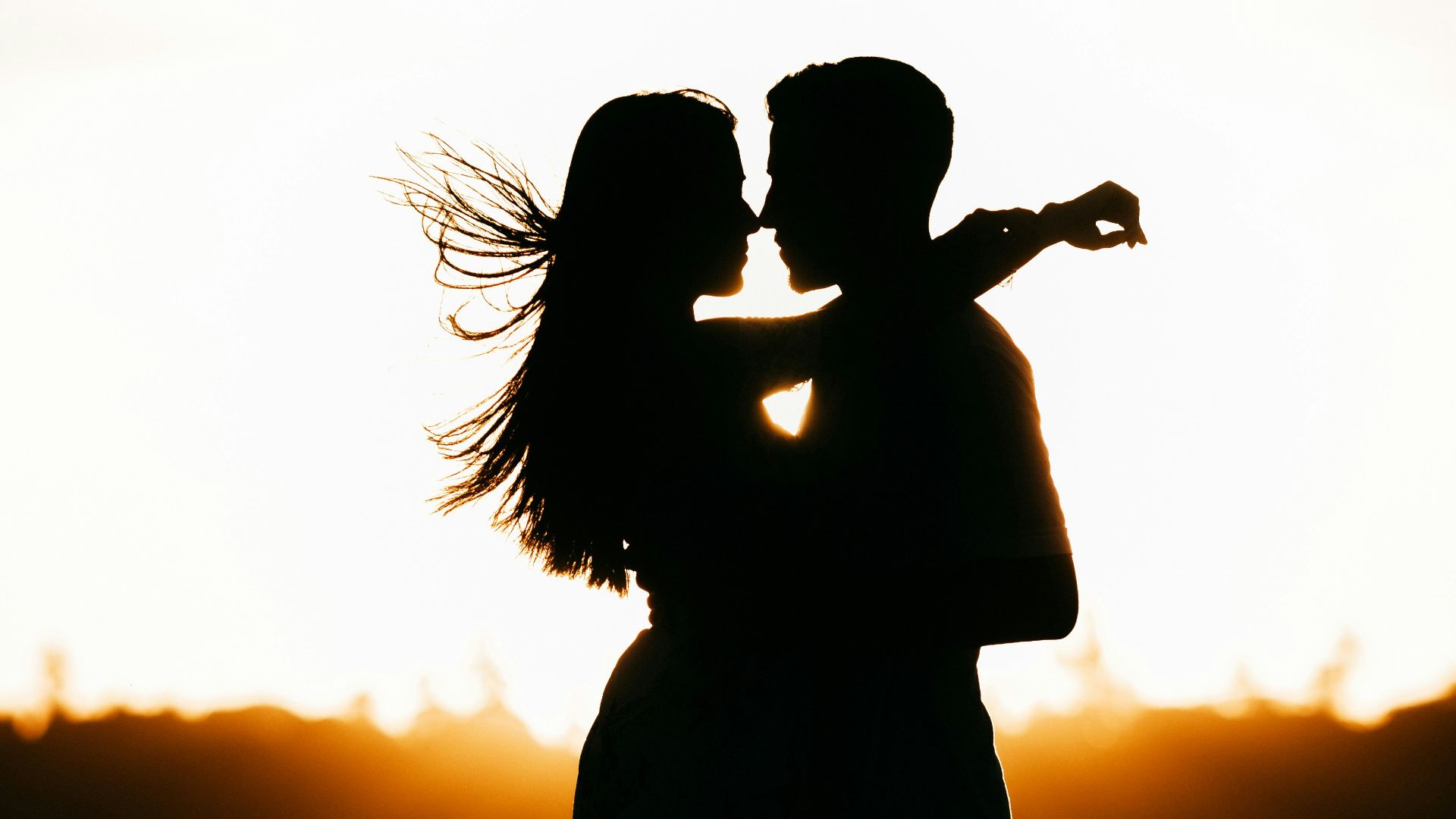 silhouette of woman standing on beach during sunset