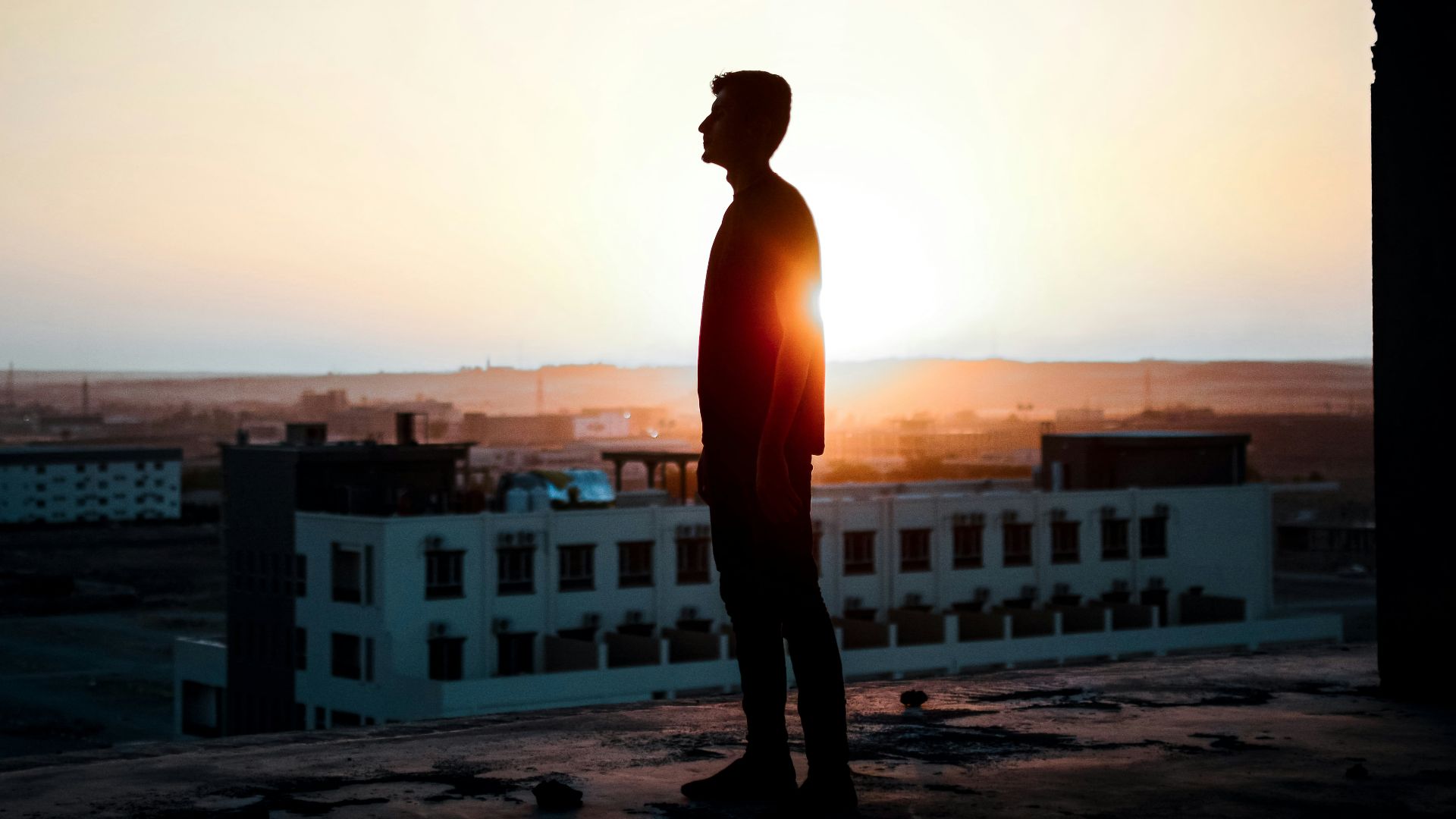 a man standing on top of a roof next to a building