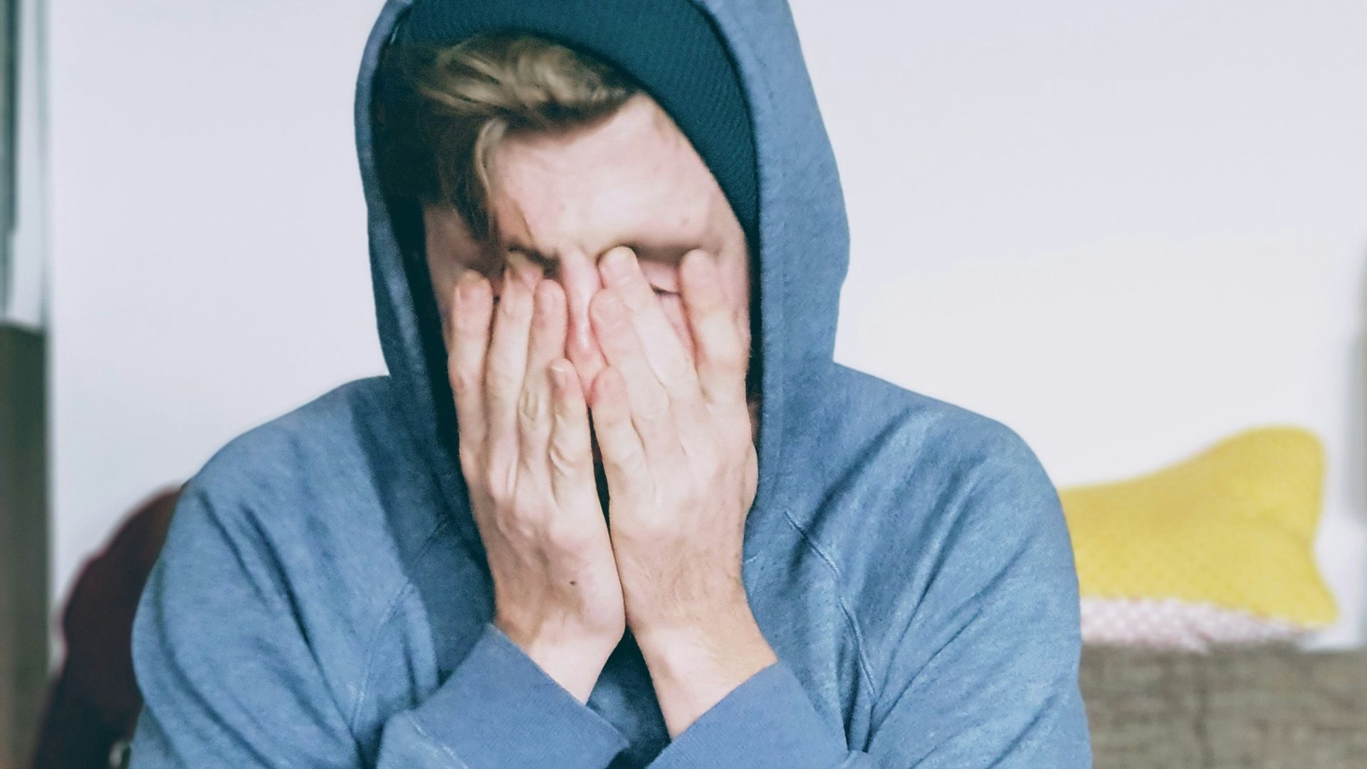 man covering face with both hands while sitting on bench