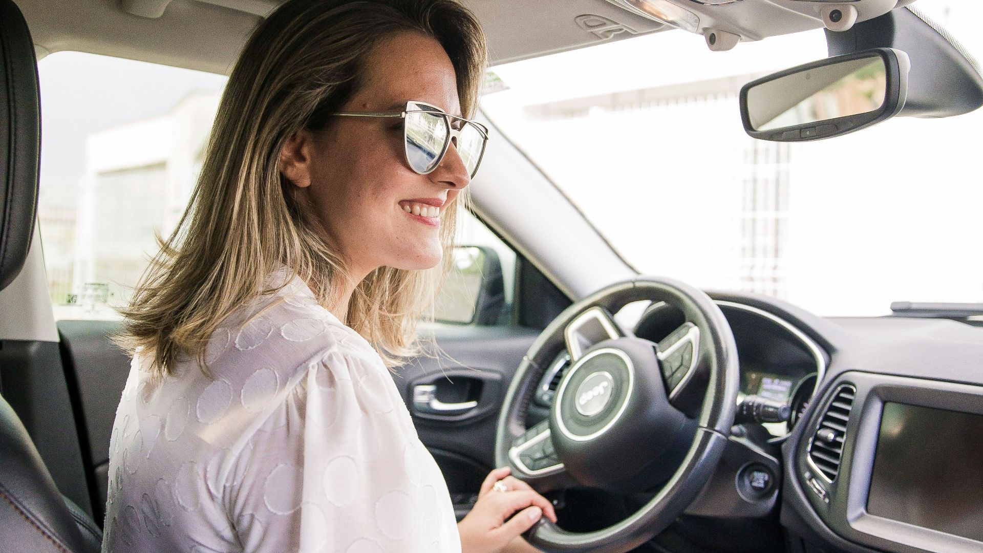 woman in white long sleeve shirt driving car