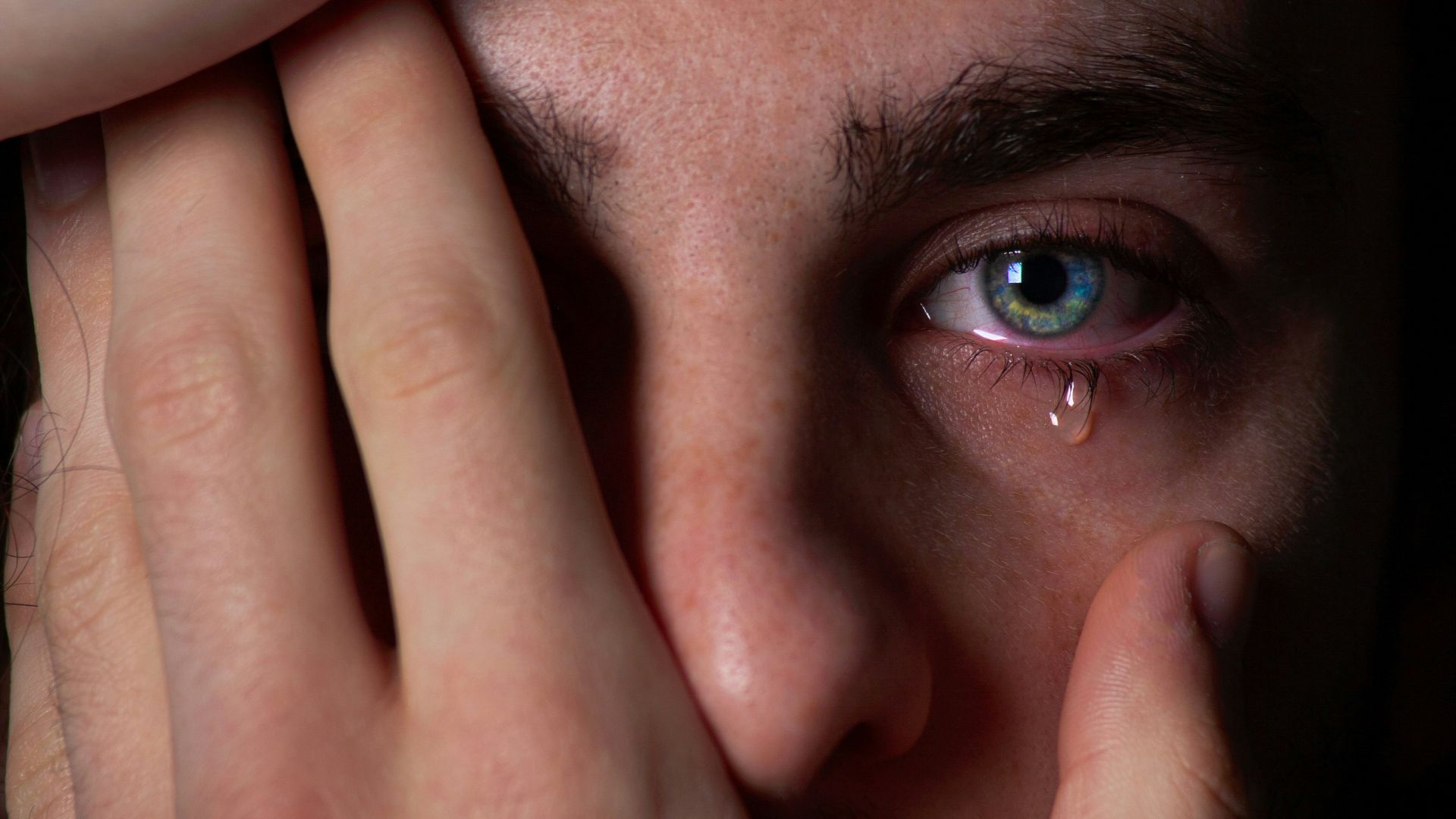 a close up of a person covering their face with their hands