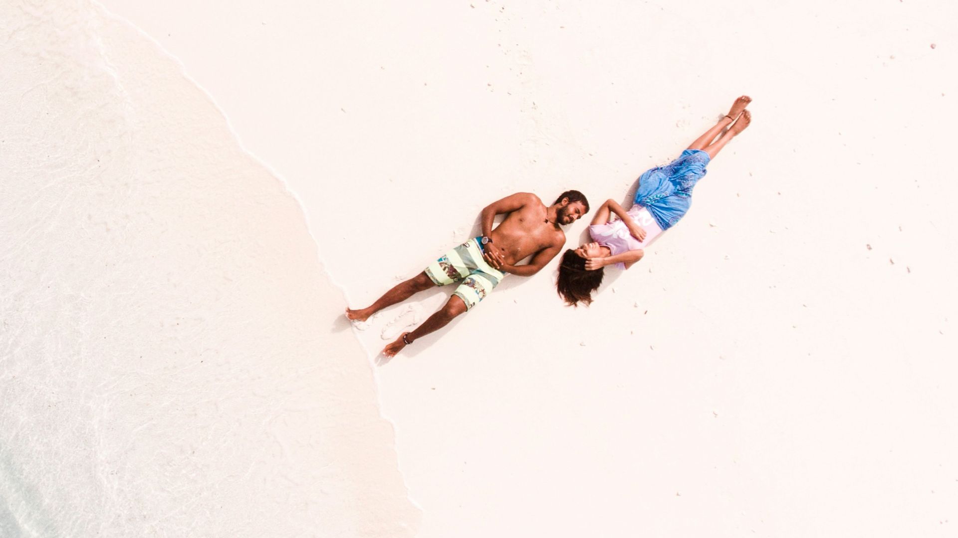 bird's eye view of man and woman lying on shore