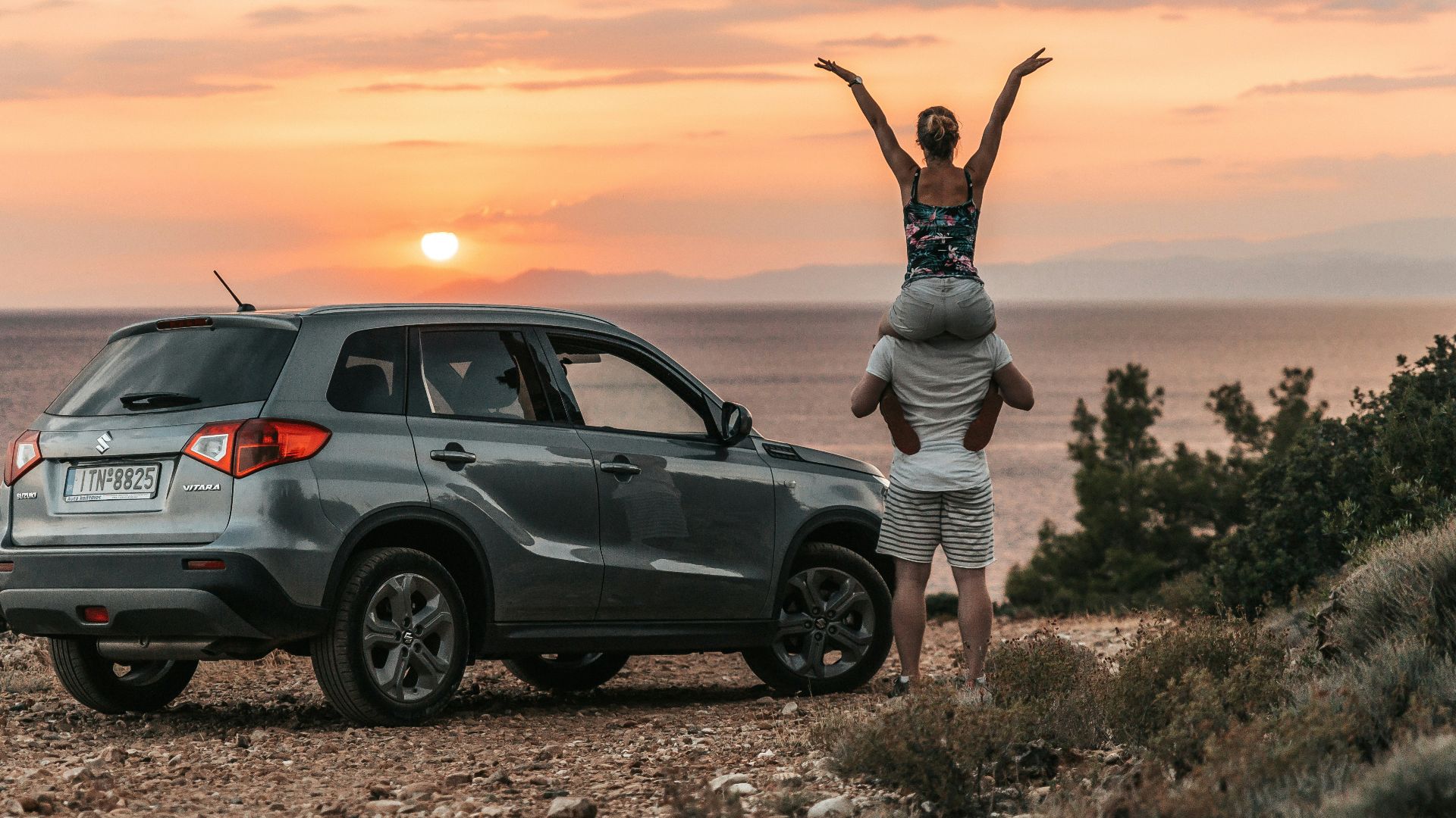 a couple of people standing on top of a car