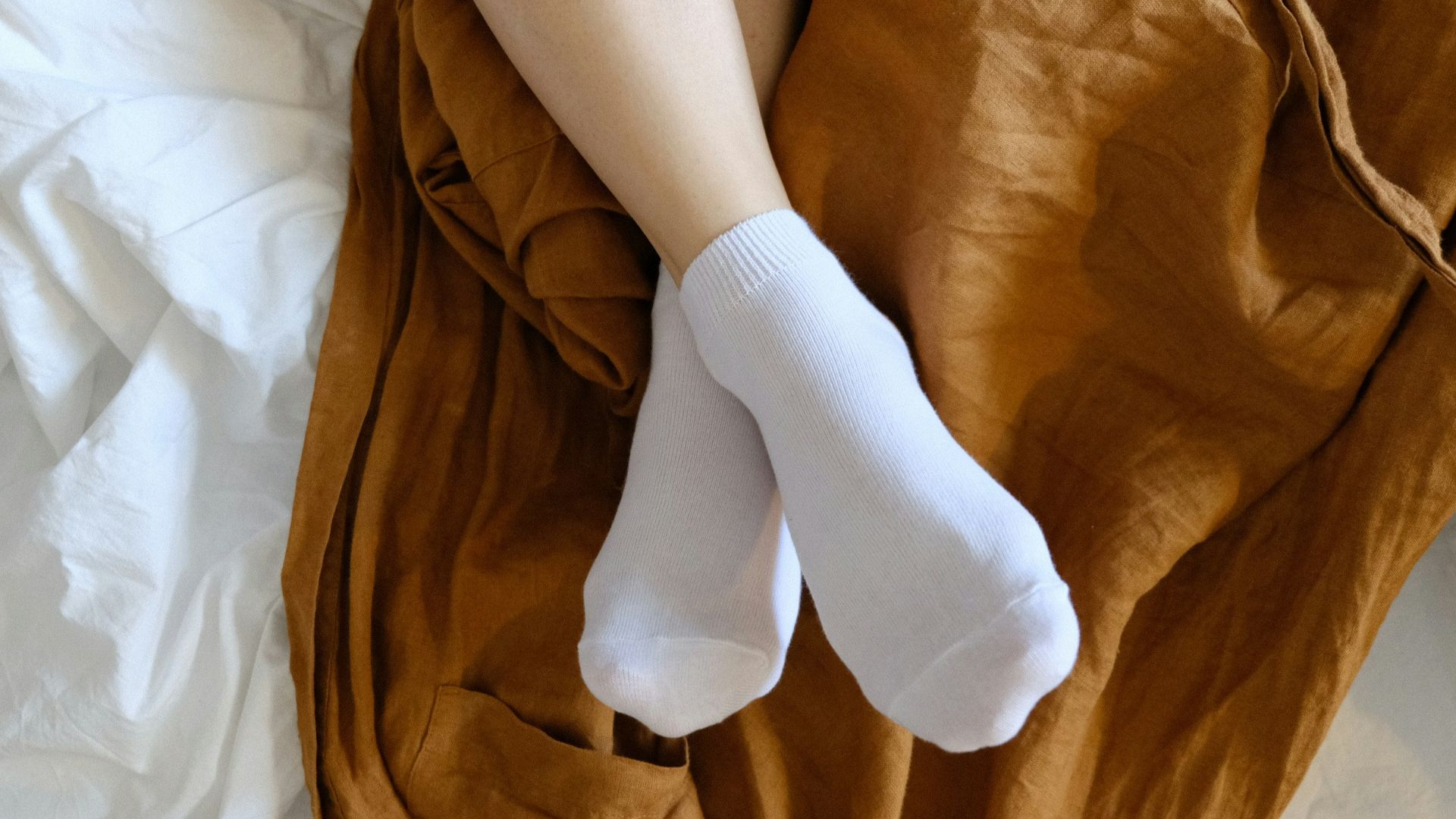 person wearing white socks lying on bed