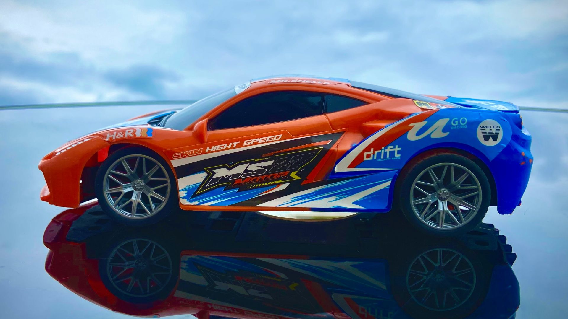 Orange and blue drift remote control car on reflective surface