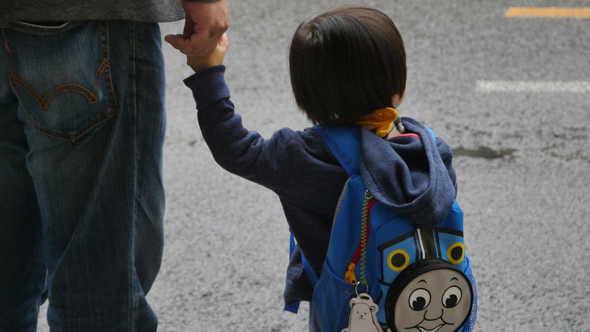 a little boy holding the hand of a man