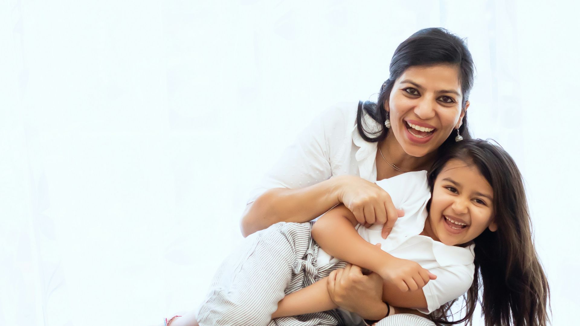 2 women sitting on gray couch