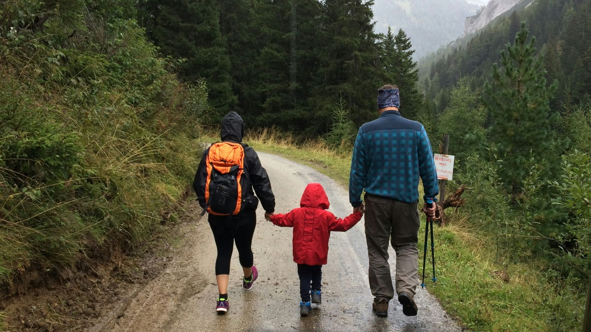 man, woman, and child walking together along dirt road