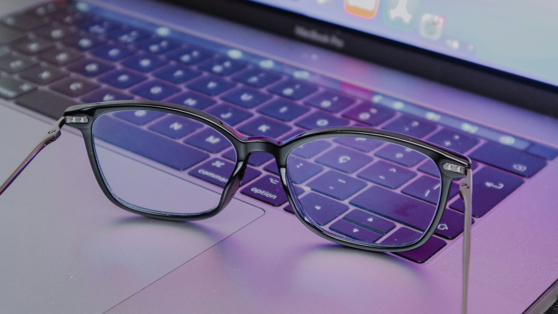 a pair of glasses sitting on top of a laptop keyboard