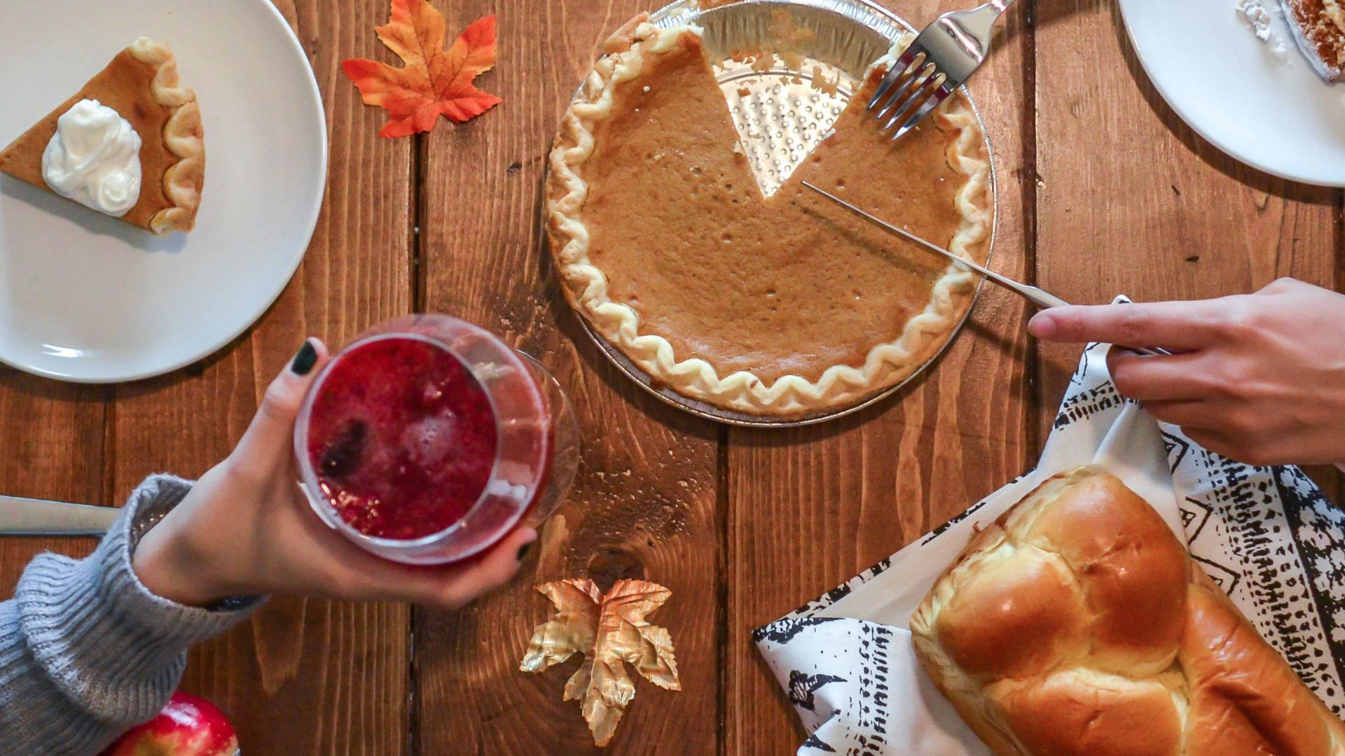 person slicing pie beside bread
