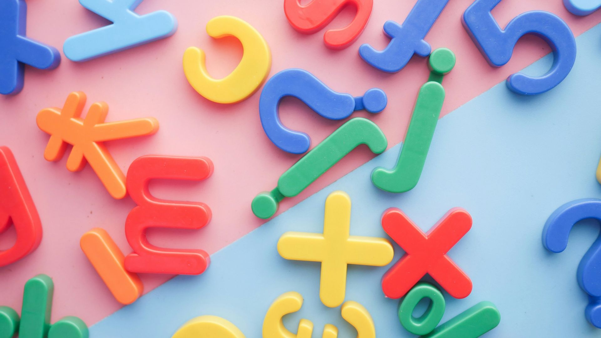 a pile of plastic letters and numbers on a pink and blue background