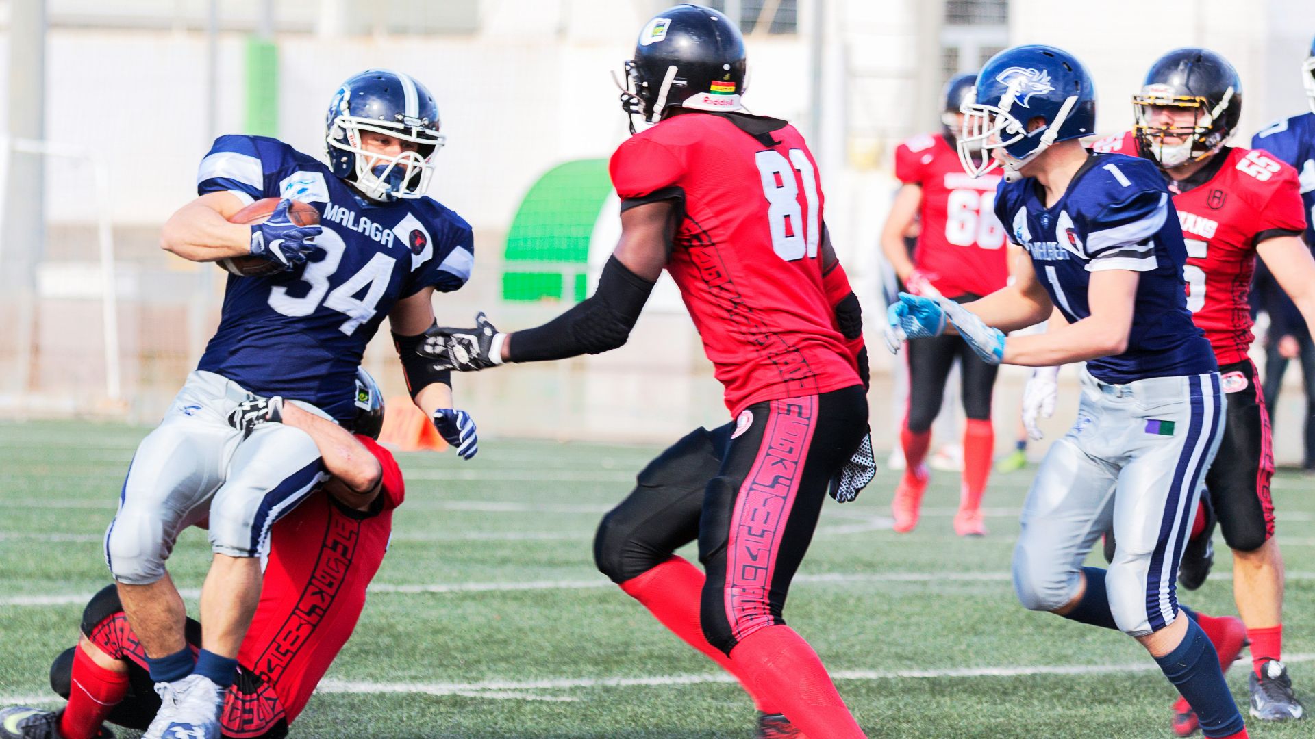 football players in red jersey shirt and red pants running on green grass field during daytime