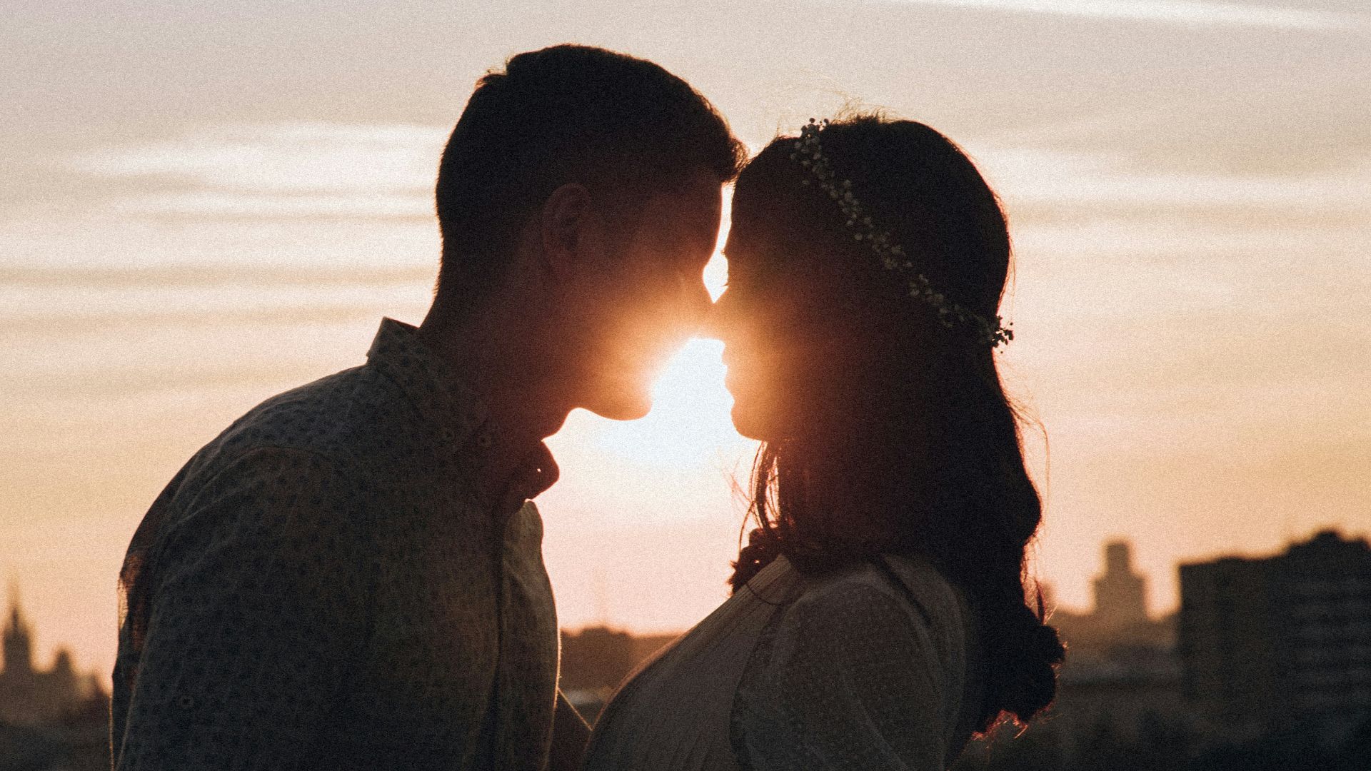 a man and a woman standing in front of a sunset