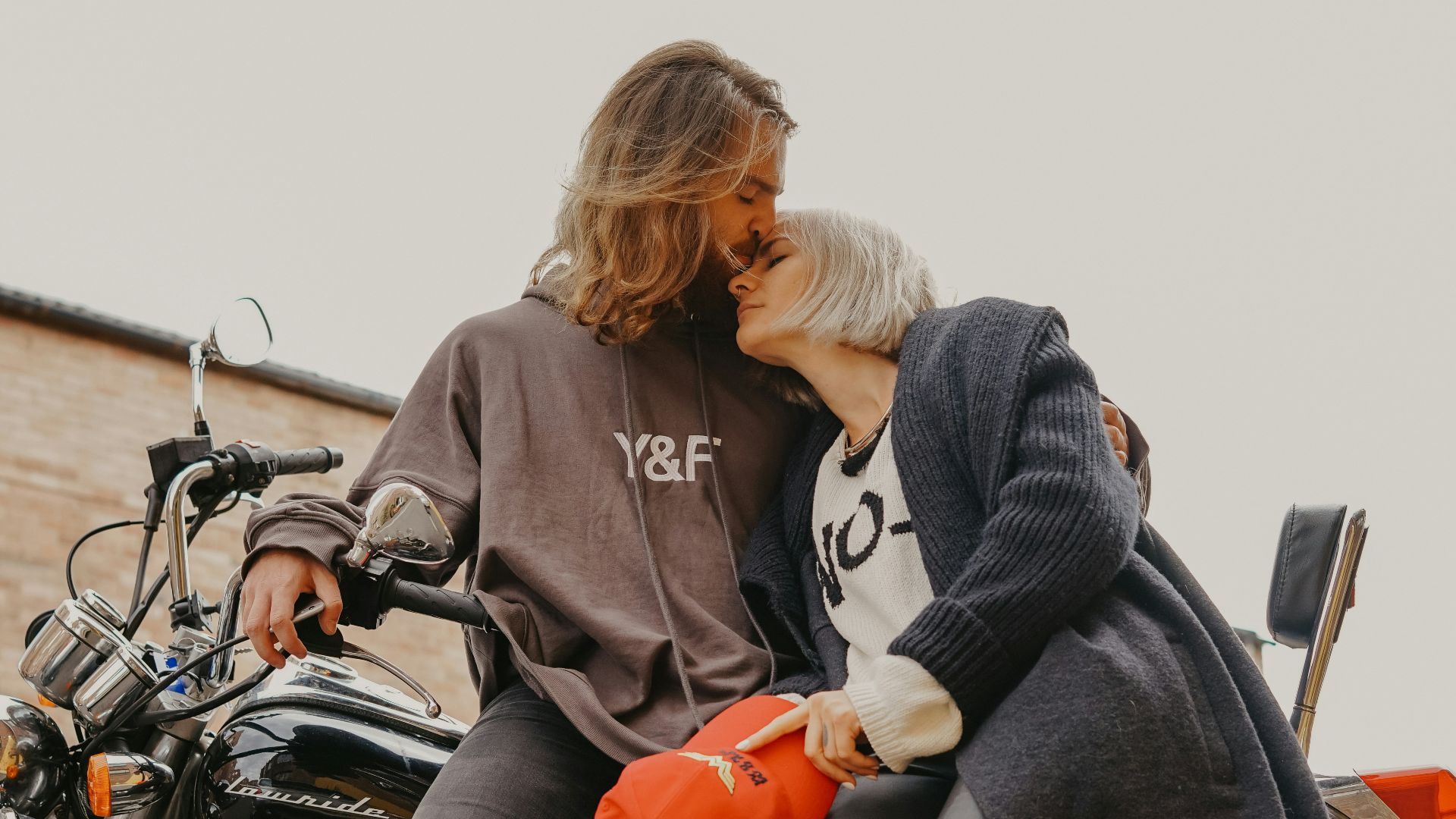 man kissing woman's forehead while sitting on motorcycle