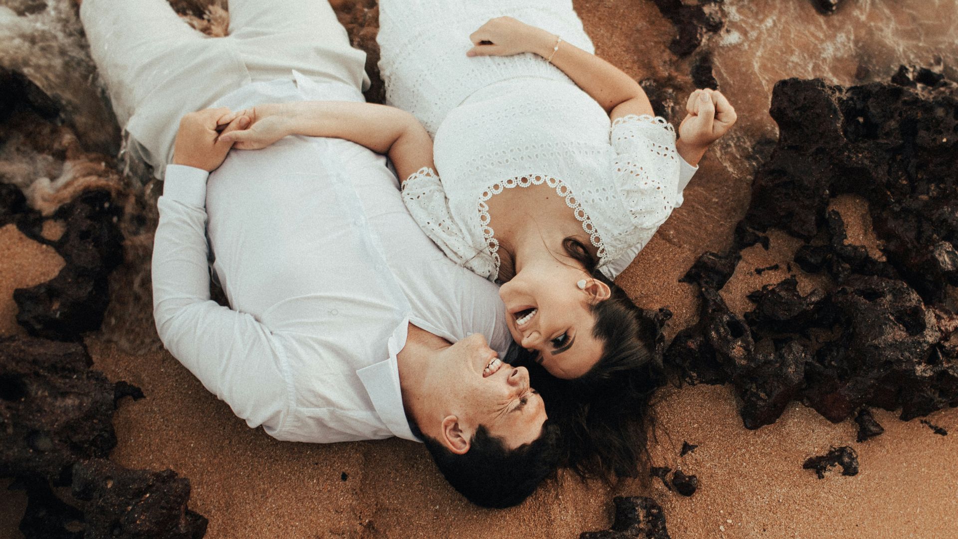 girl in white long sleeve shirt lying on brown sand during daytime