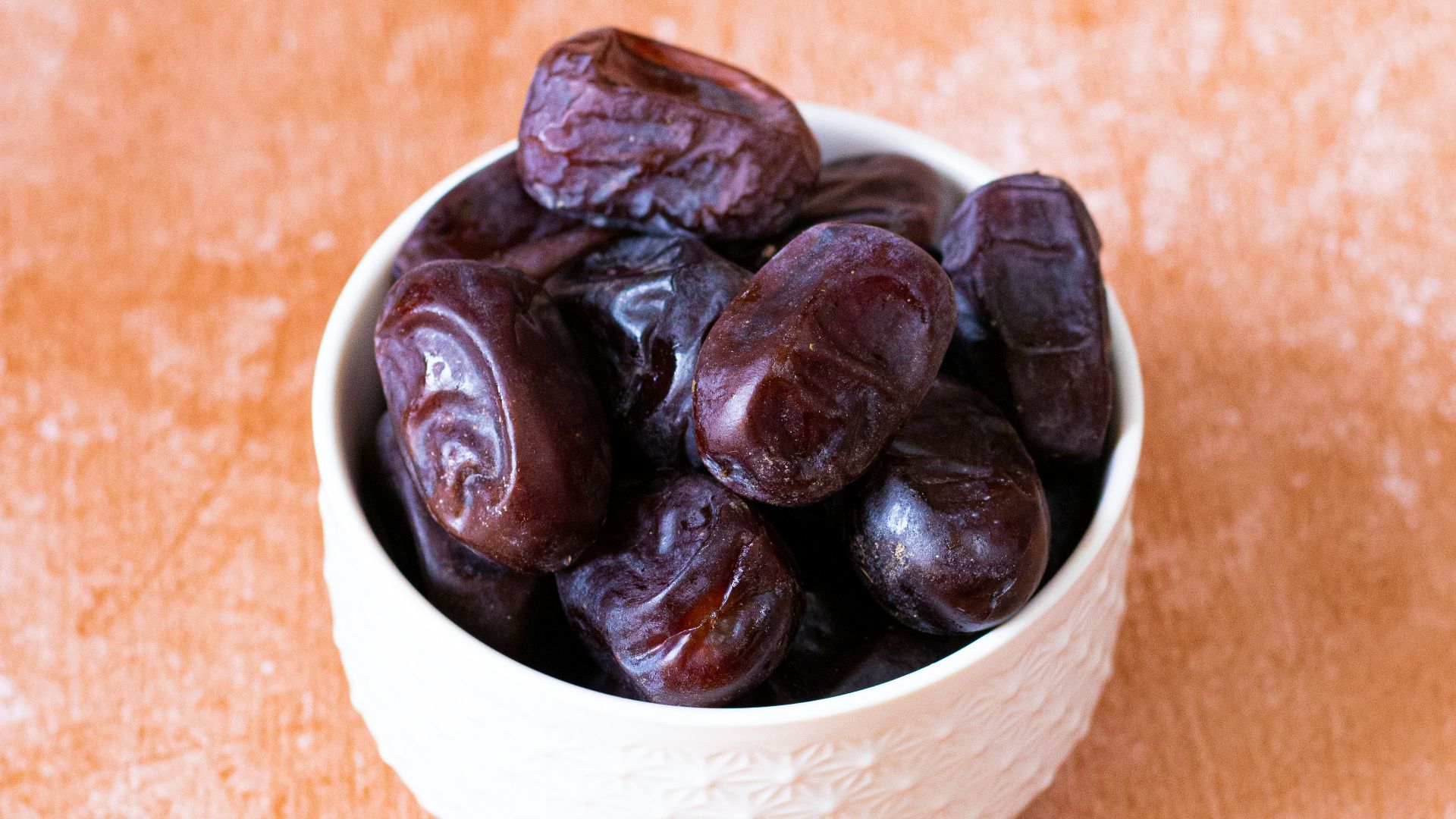 a white bowl filled with raisins on top of a wooden table