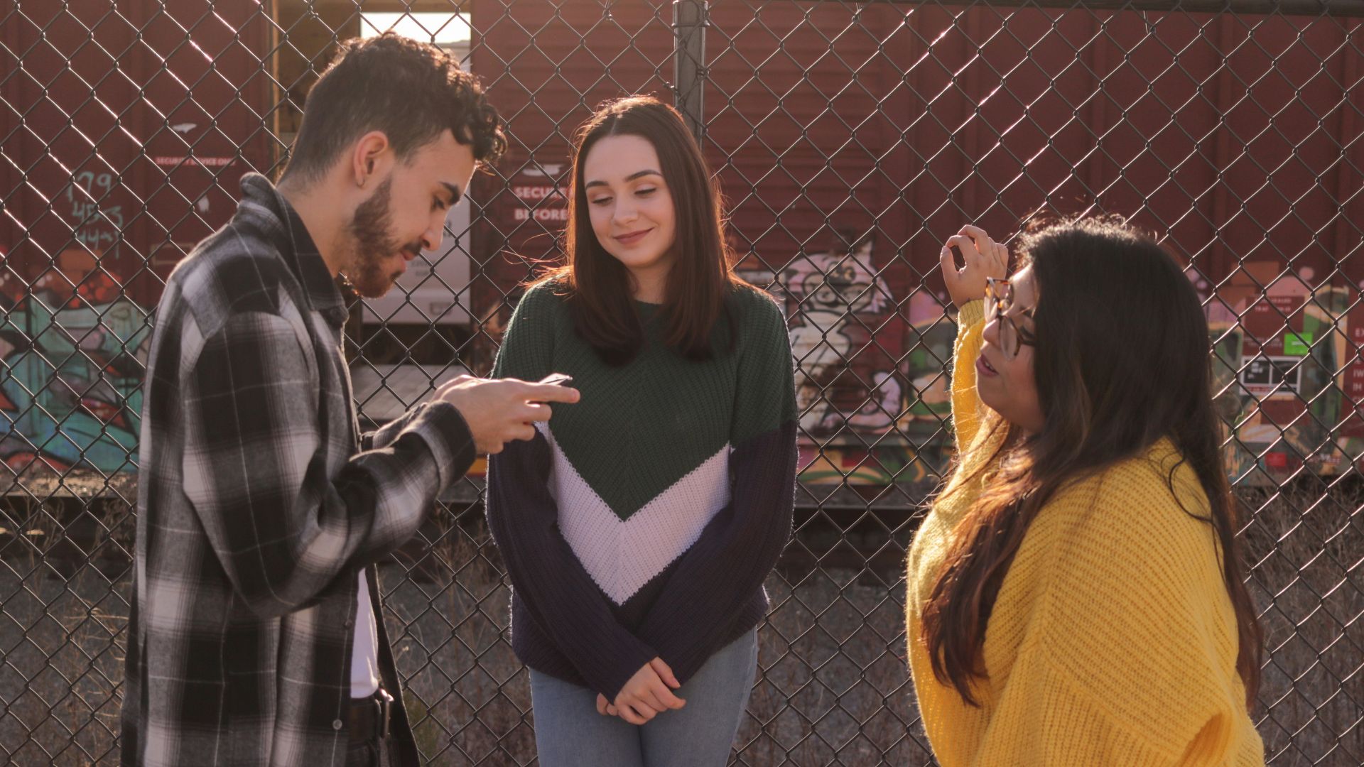 two women and one man standing near fence